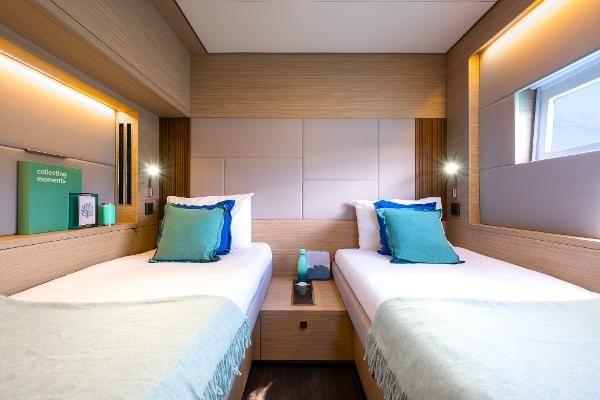 Luxurious twin cabin interior of 2025 Lagoon 60 yacht, featuring modern design and cozy bedding.