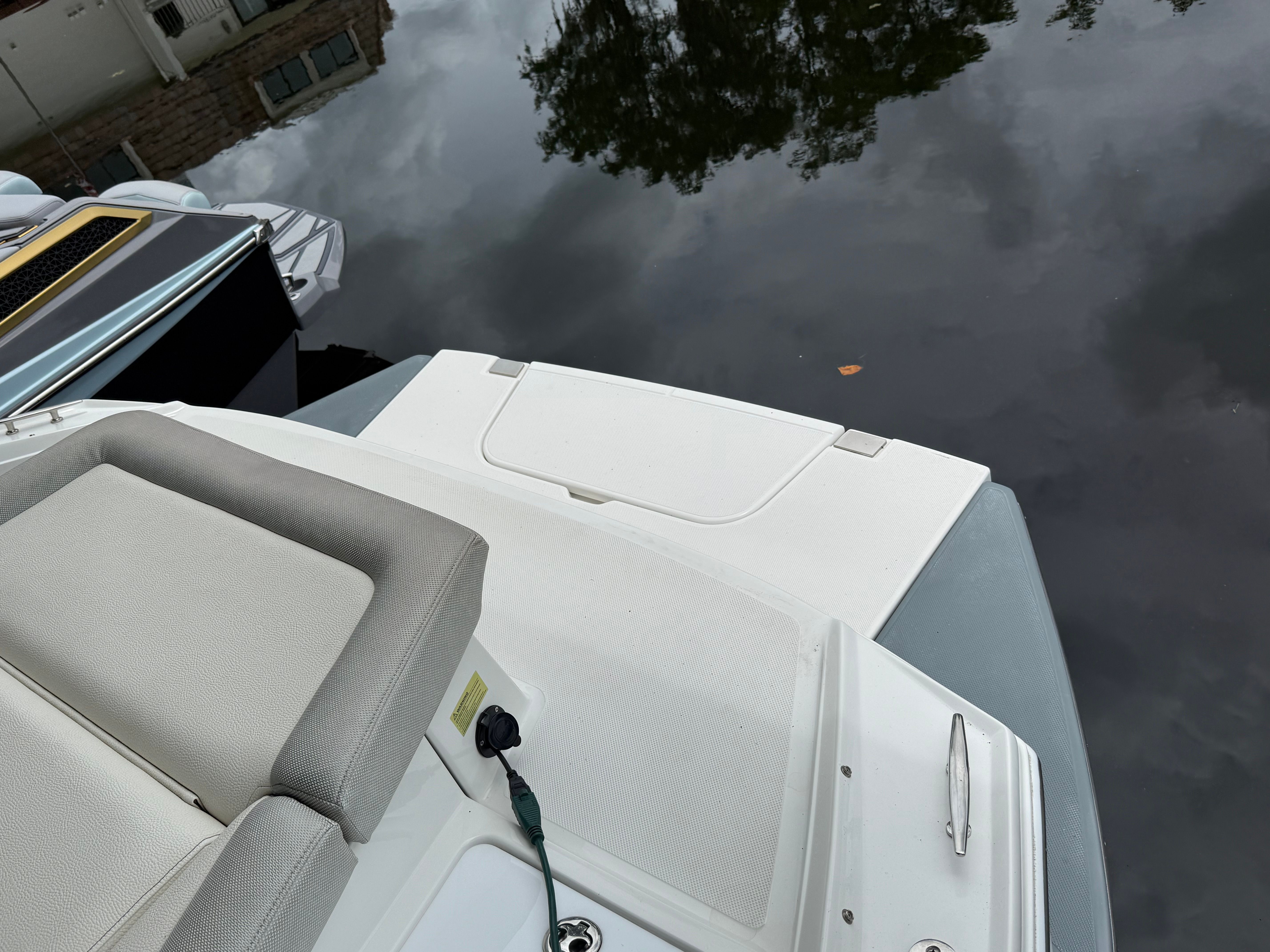 A boat with gray upholstery and a white platform on calm water.