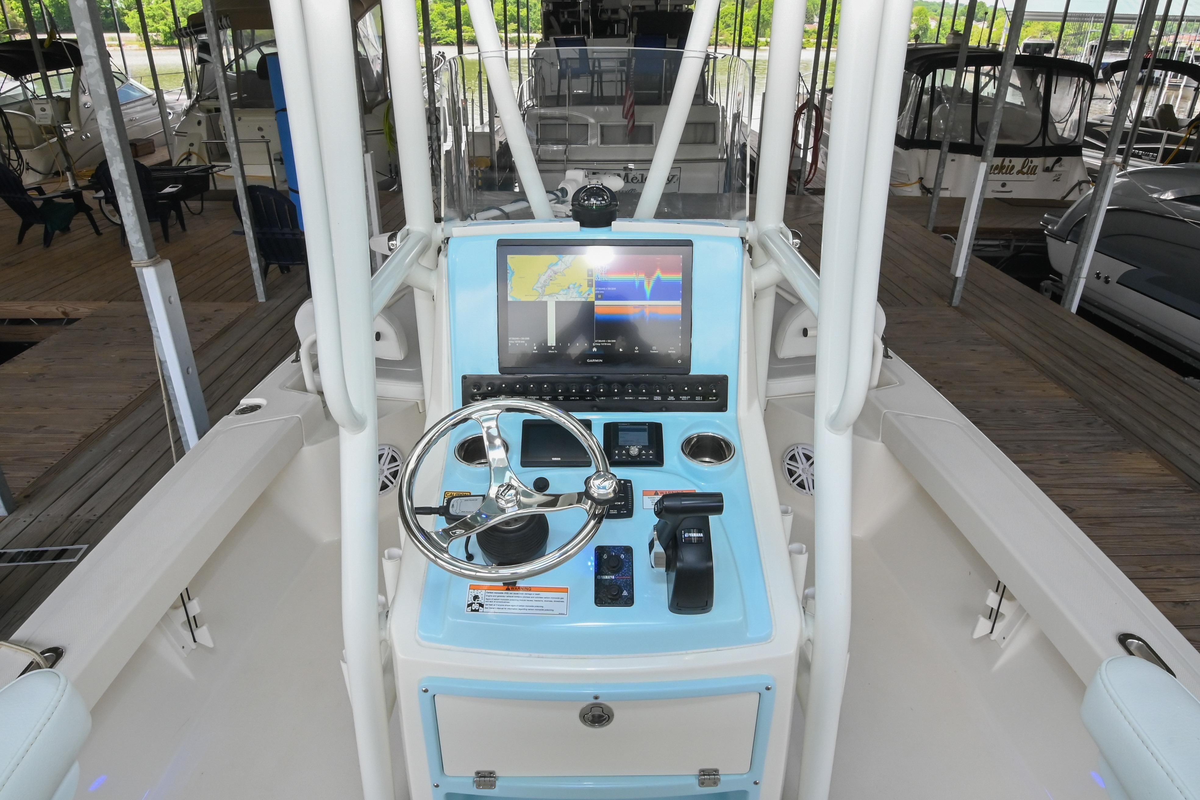 2025 Pathfinder 2200 TRS boat console with steering wheel and navigation display in marina.