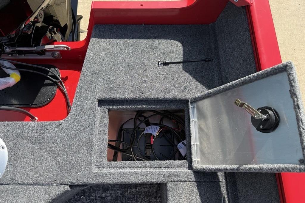 Open storage compartment in 2026 Tracker Pro Guide V-16 SC boat, showing wiring and carpeted interior.