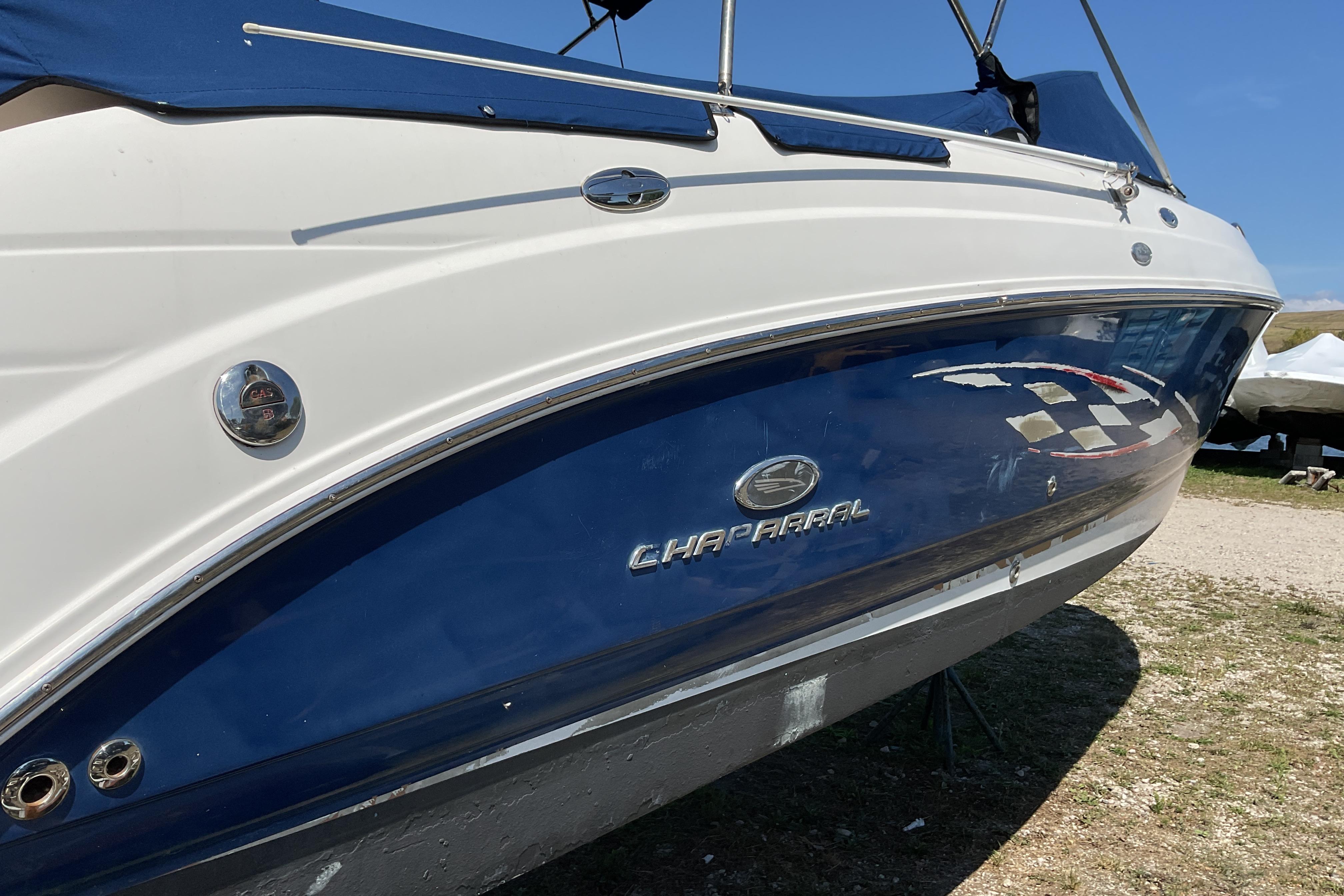 2006 Chaparral 256 SSi boat with blue and white exterior, parked outdoors.