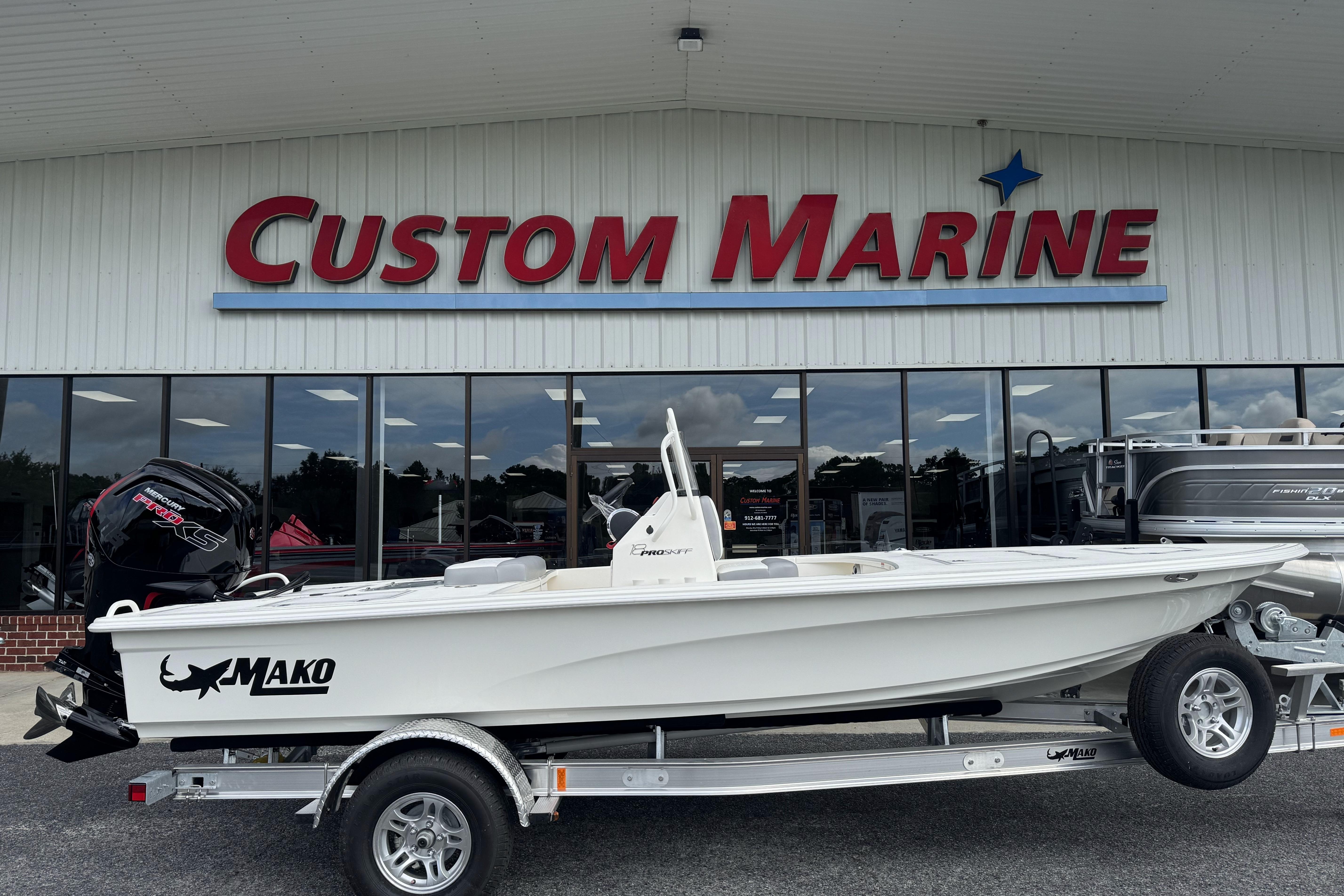 2026 Mako 18 Pro Skiff boat on trailer outside Custom Marine store.