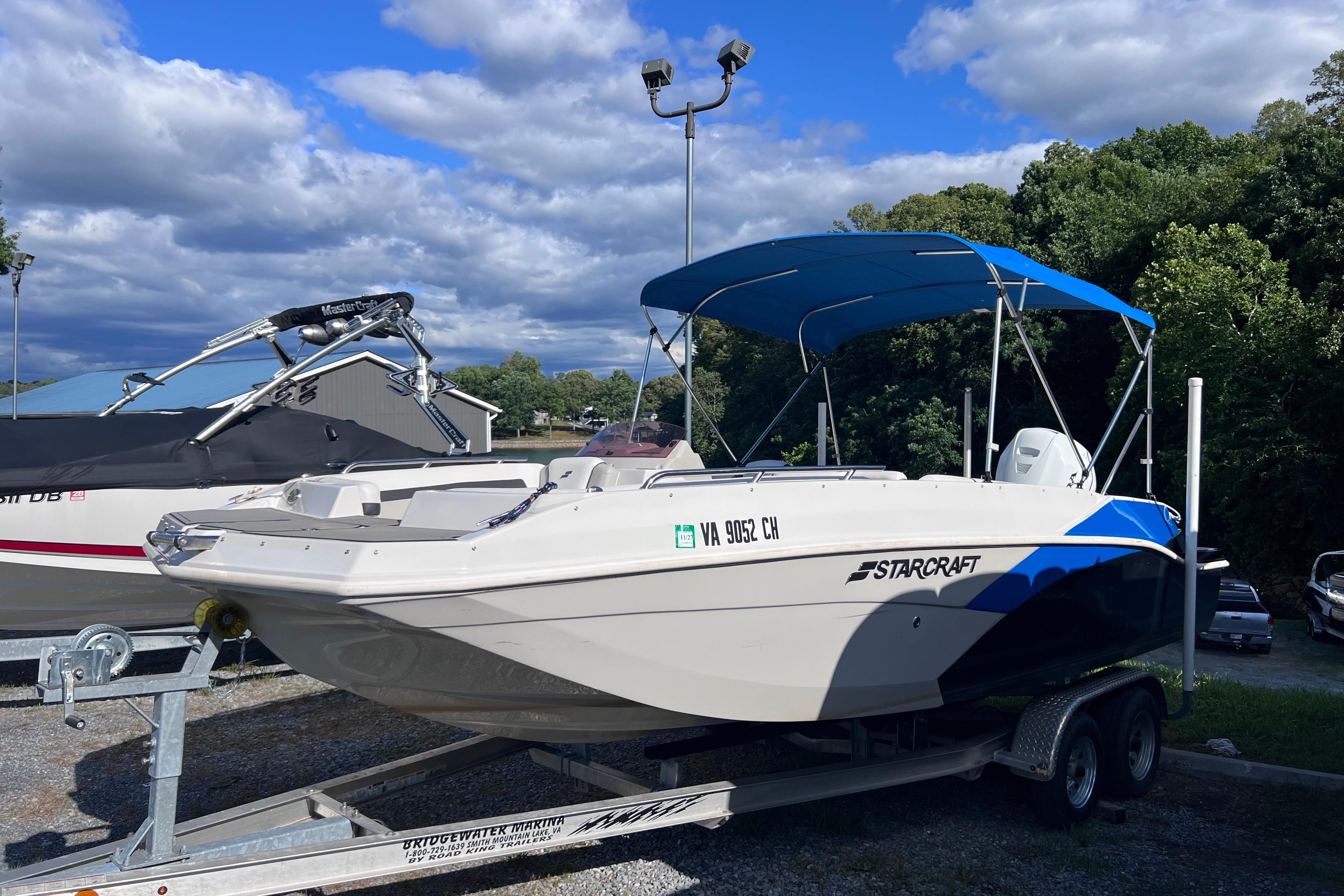 2021 Starcraft SVX 211 OB boat on trailer with blue canopy, parked outdoors.