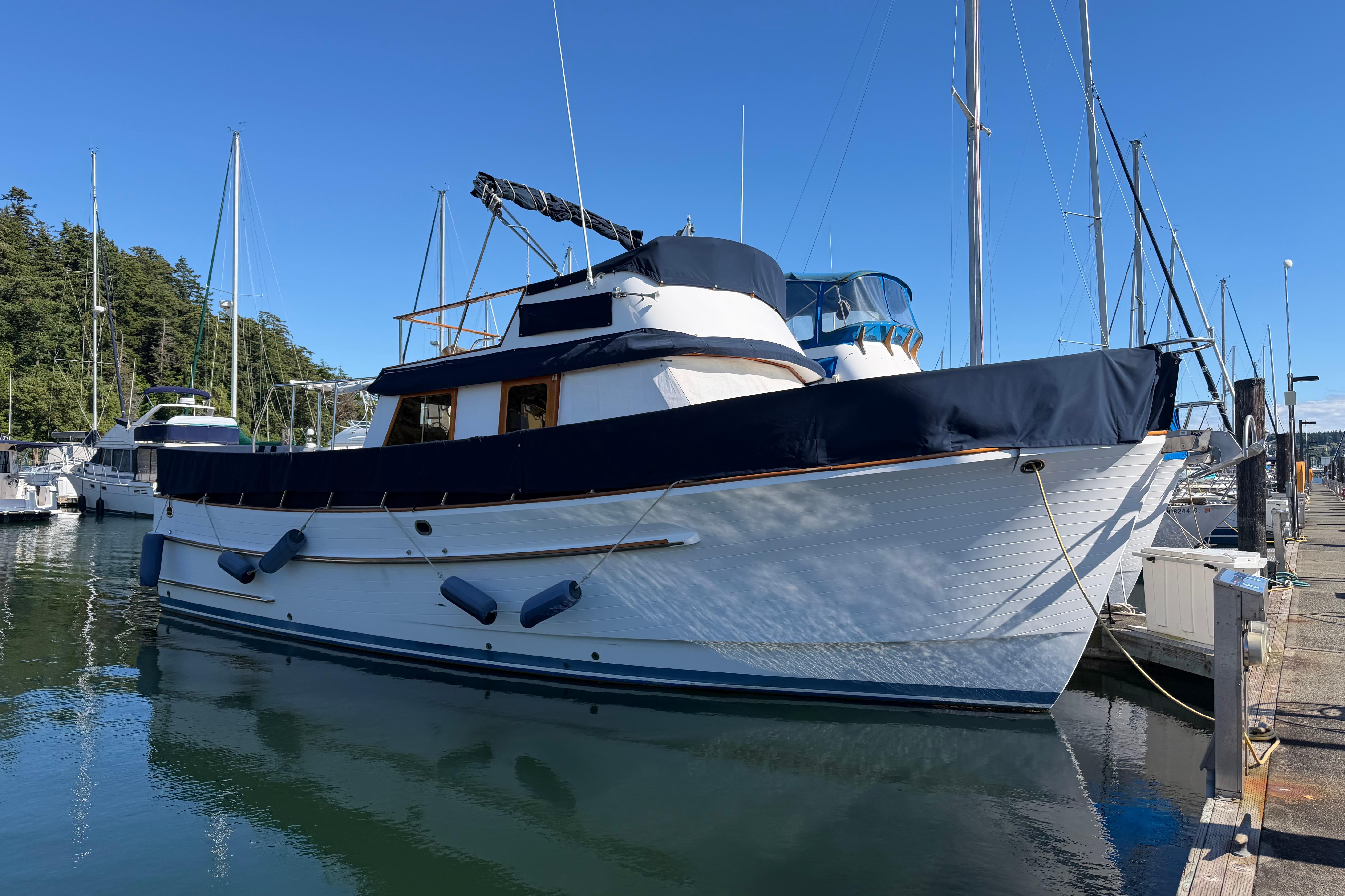 1988 Monk 36 yacht docked at marina, featuring classic design and blue accents.