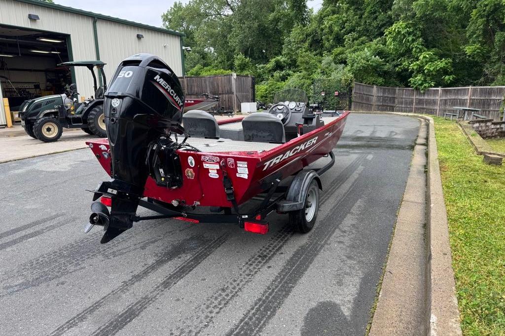 2022 Tracker Pro 170 boat with Mercury engine on trailer, parked near a workshop.