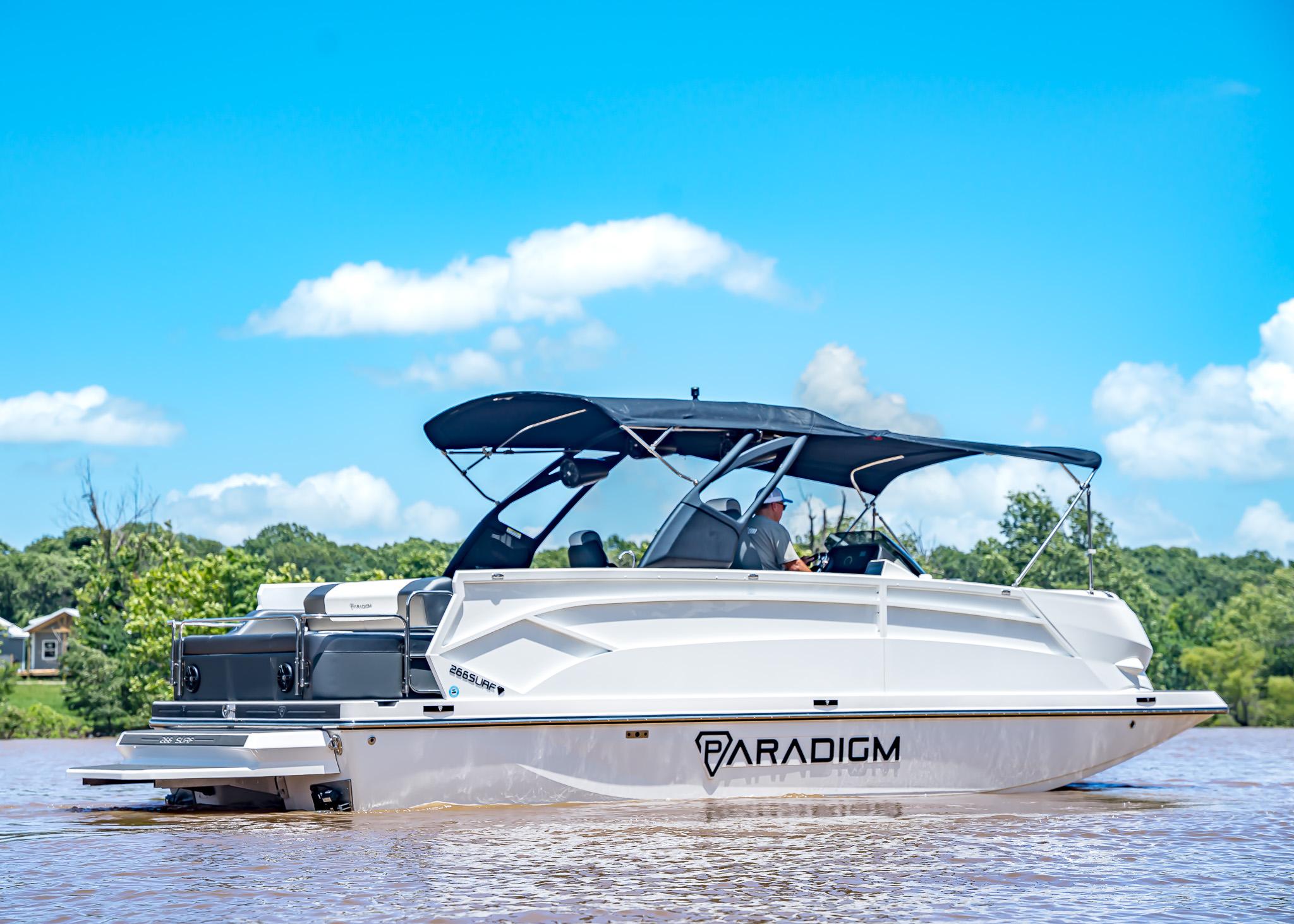 2025 Paradigm Damascus 266 Surf boat on a sunny day, cruising on a lake.