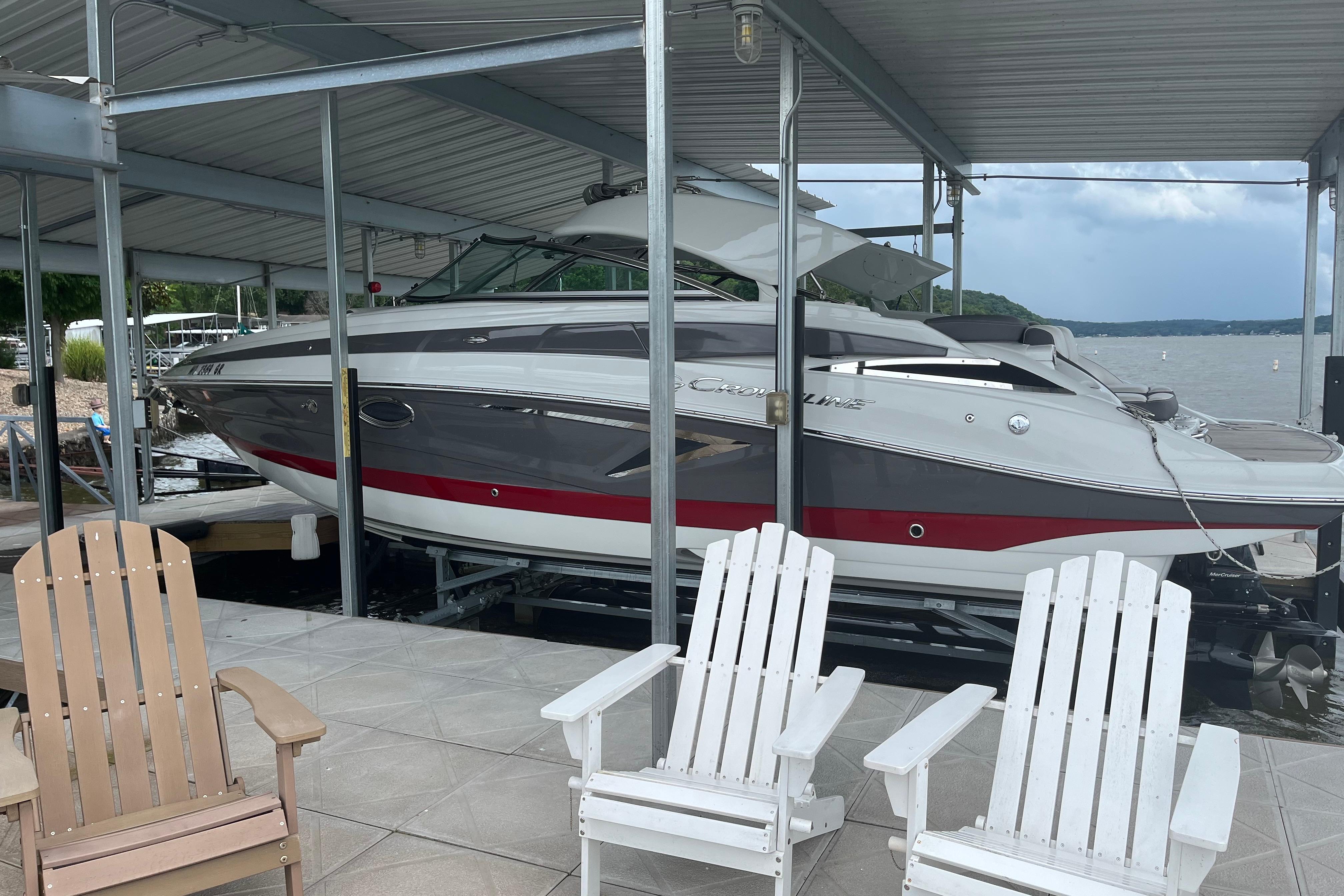 2022 Crownline 265 SS boat docked under a covered marina with lake view.
