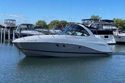 2017 Rinker EX 320 boat docked in a marina under clear blue skies.