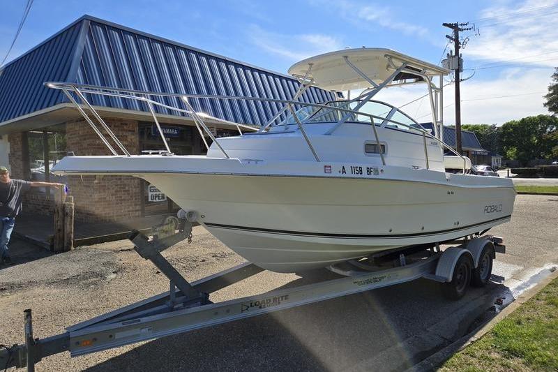 2004 Robalo R235 Walkaround boat on trailer outside a building.