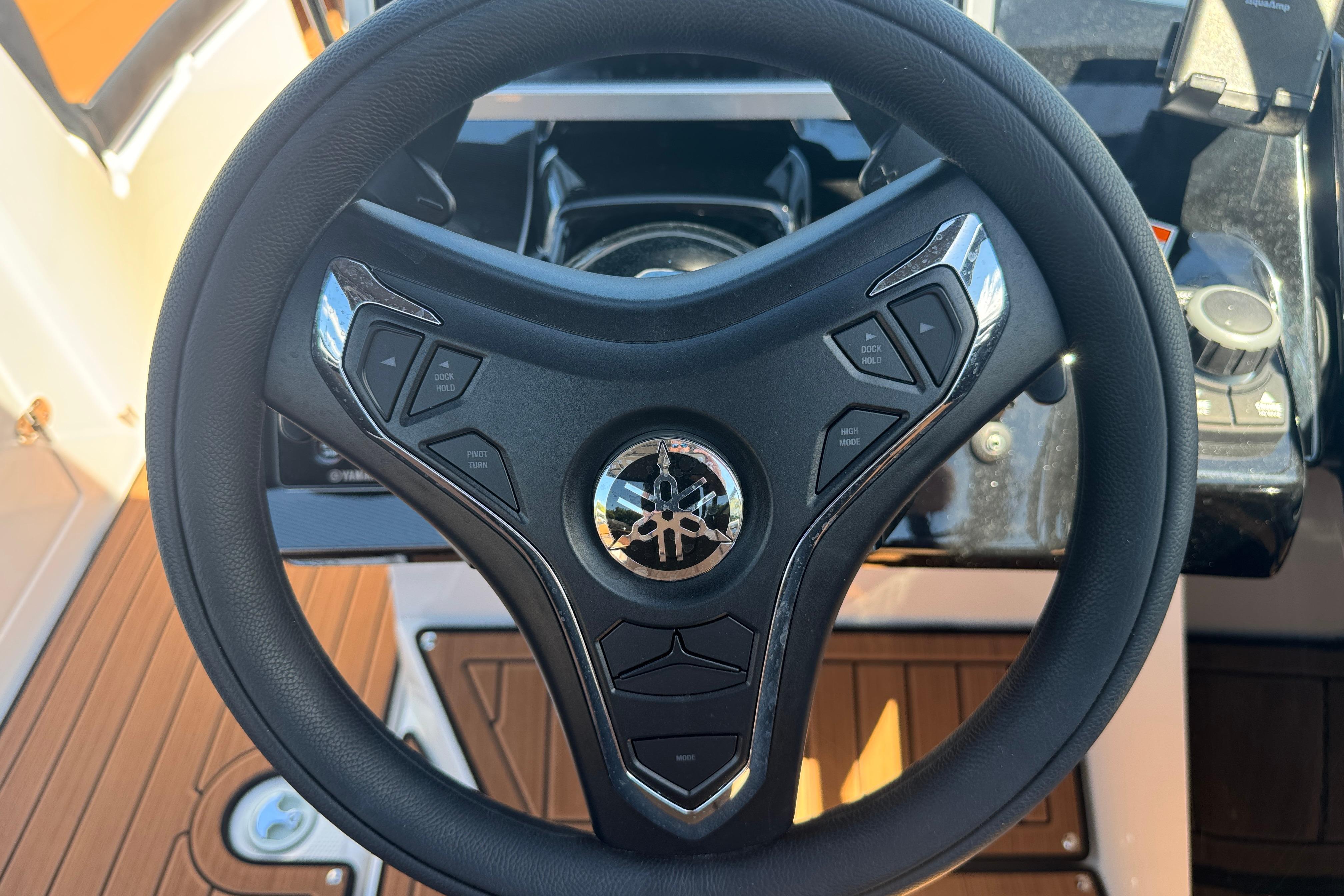 Steering wheel of 2026 Yamaha Boats 252SD, featuring control buttons and sleek design.