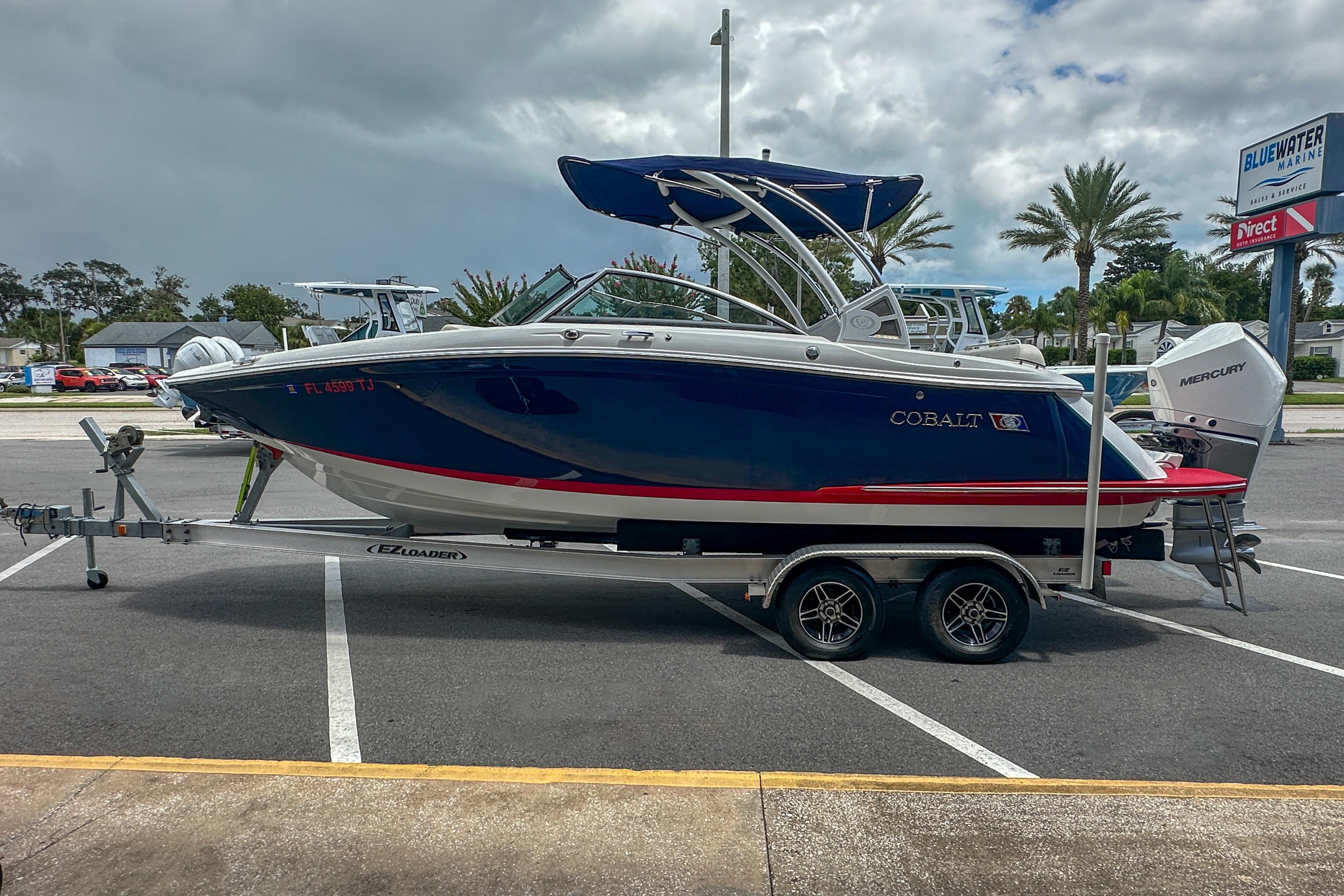 2022 Cobalt 25SC boat on trailer in parking lot, cloudy sky background.
