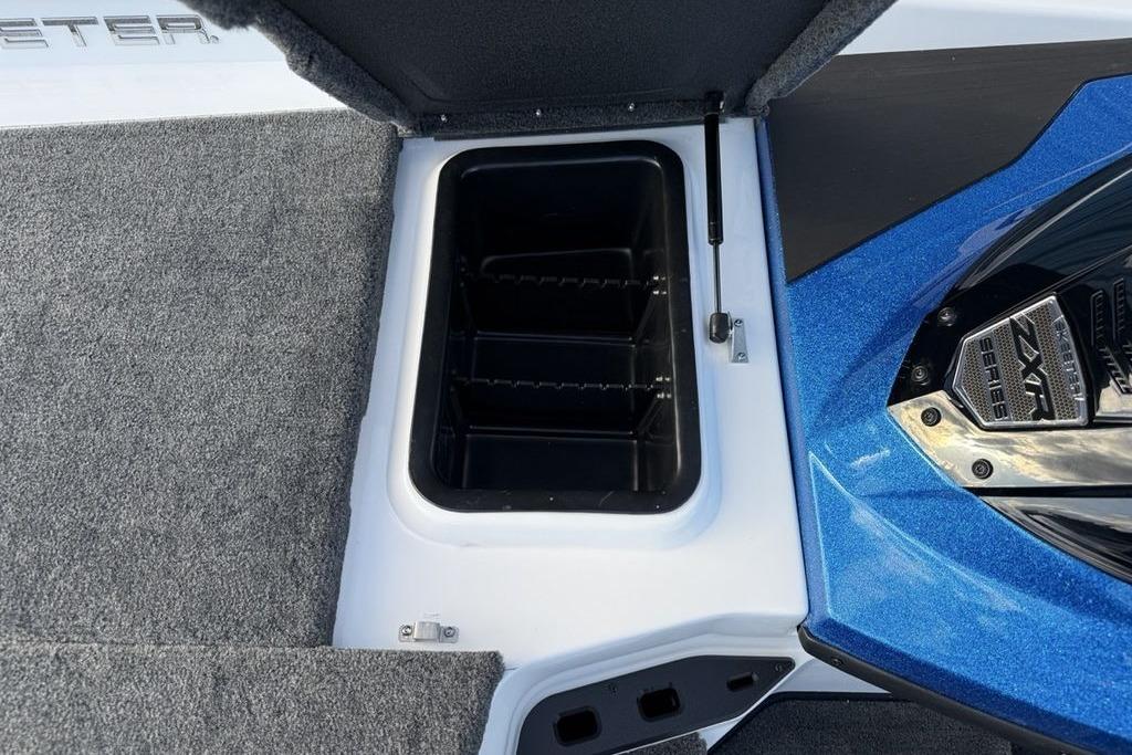 Open storage compartment in 2026 Skeeter ZXR19 SE boat, featuring carpeted interior and blue exterior.