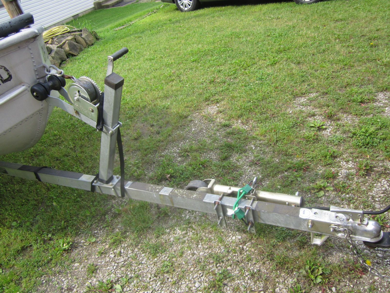 A boat trailer on a grassy area, featuring a winch and hitch.