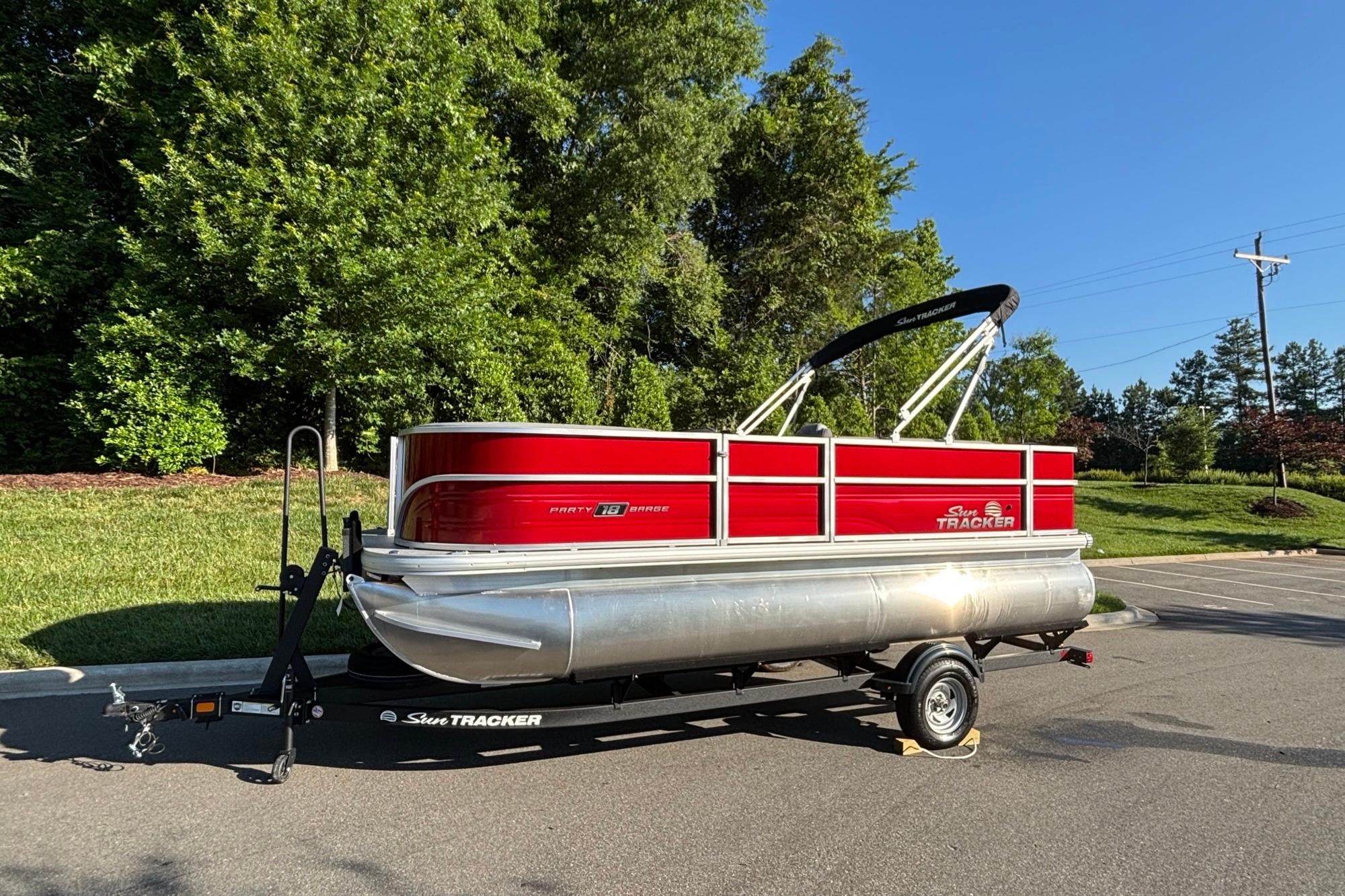 2026 Sun Tracker Party Barge 18 DLX pontoon boat on trailer, parked outdoors.