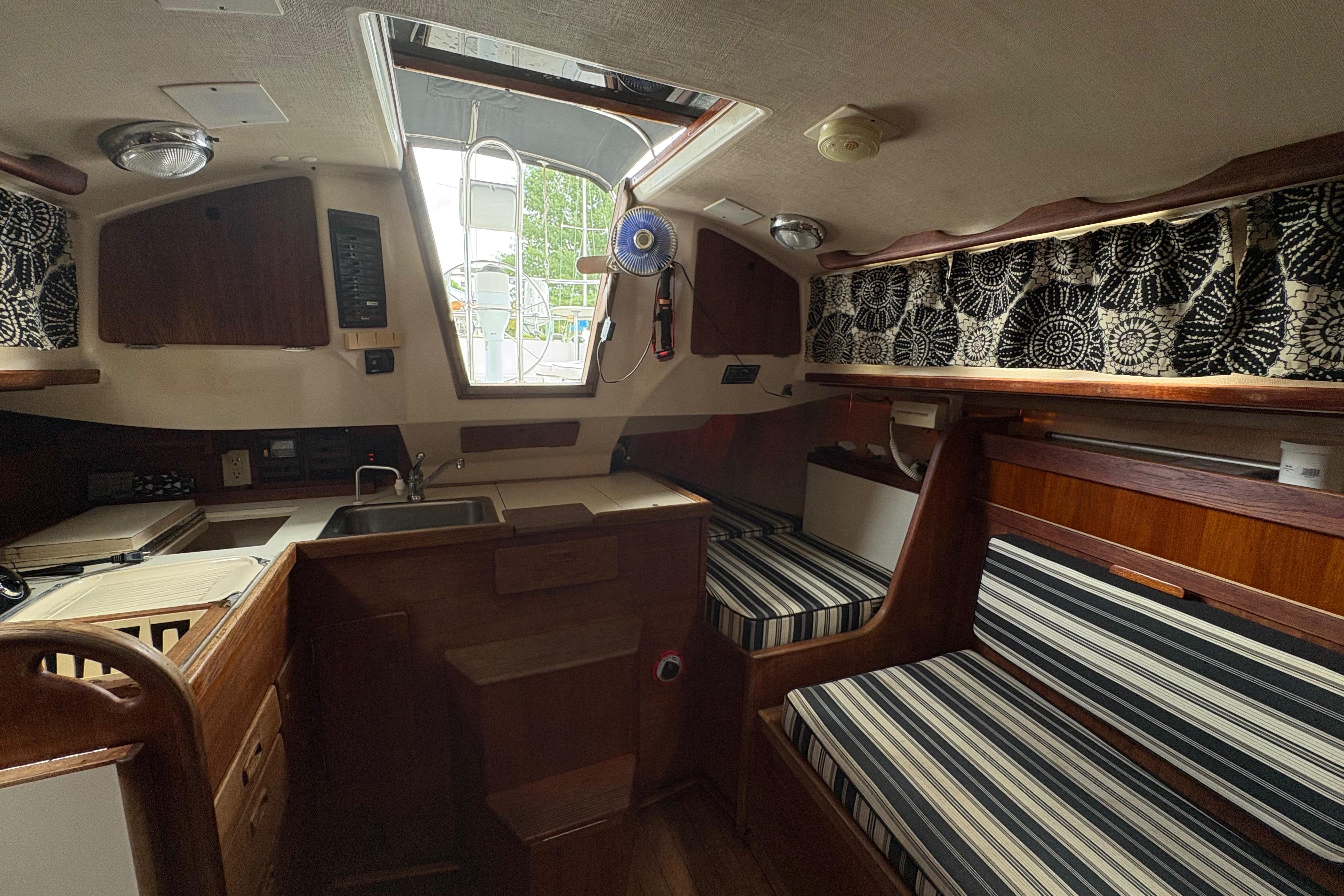 Interior of 1981 Sabre 31 sailboat with striped seating and compact kitchen area.
