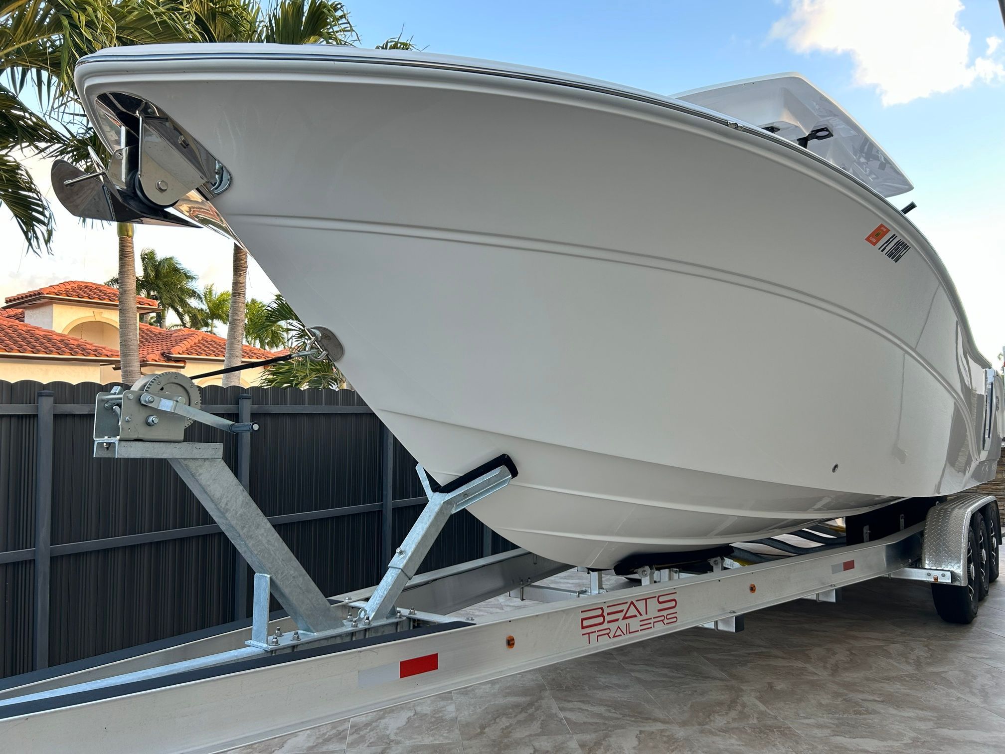 A 2023 Sea Fox 288 Commander on a trailer, surrounded by palm trees and a fence.