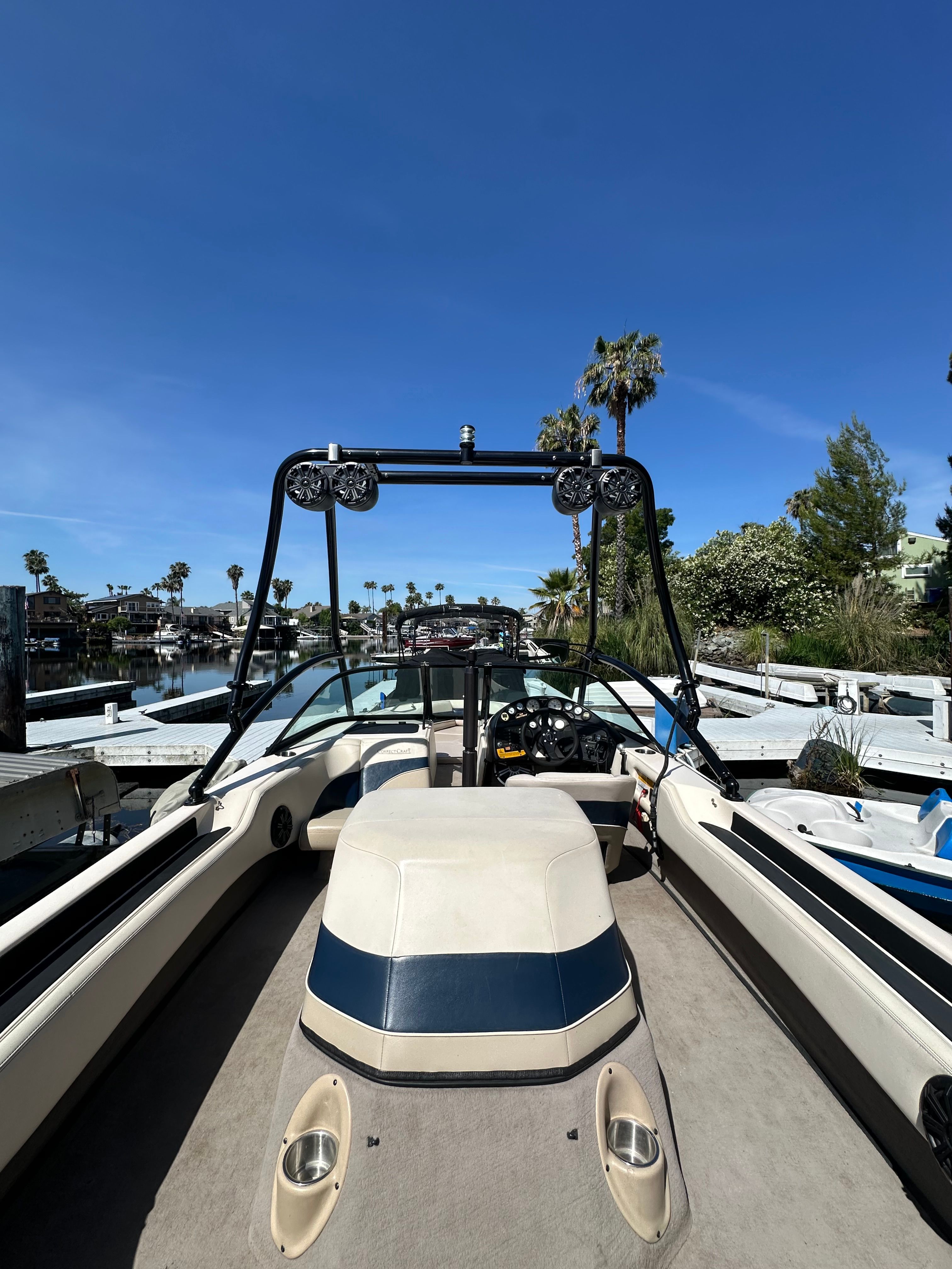 1998 Correct Craft Air Nautique boat docked under sunny skies.