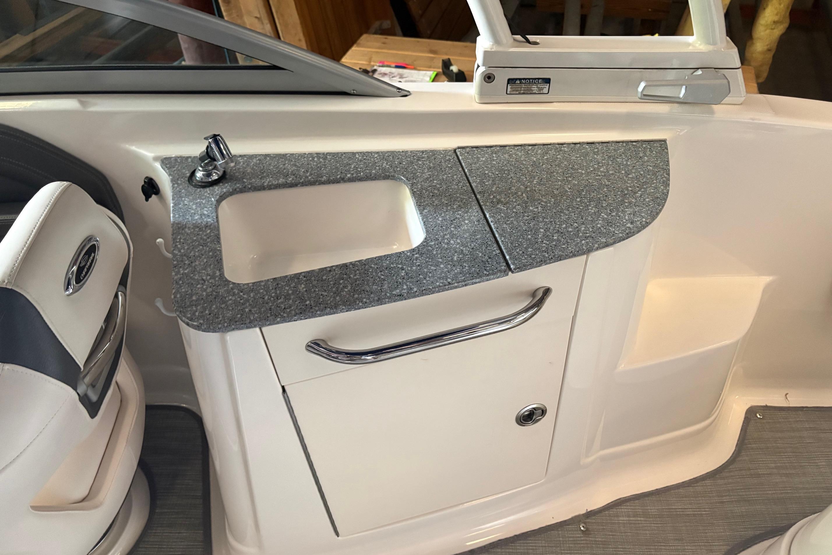 Interior of 2016 Chaparral 244 Sunesta boat featuring a compact sink and storage area.
