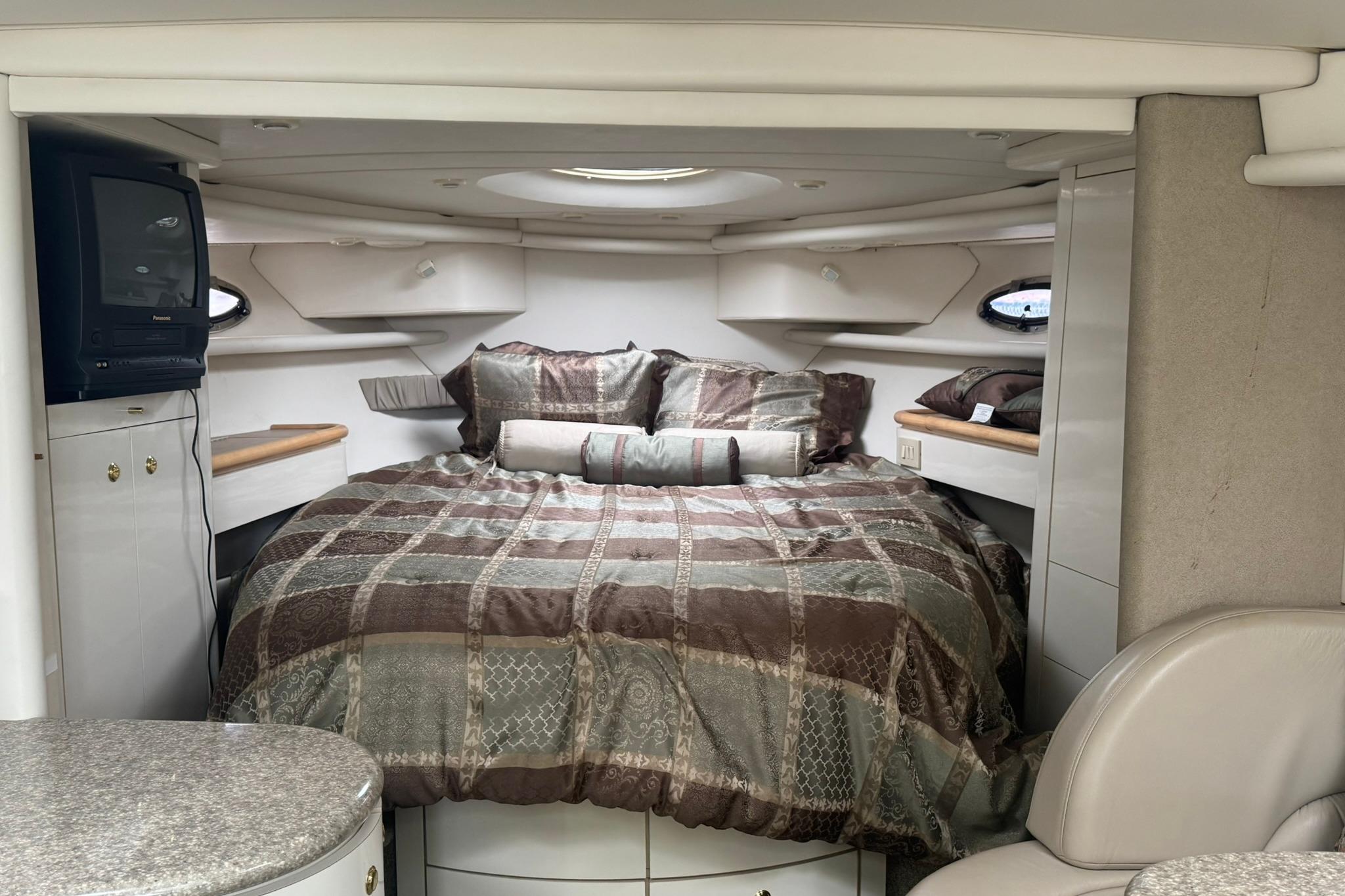 Cozy interior of 1998 Maxum 3700 SCR yacht with bed and TV.