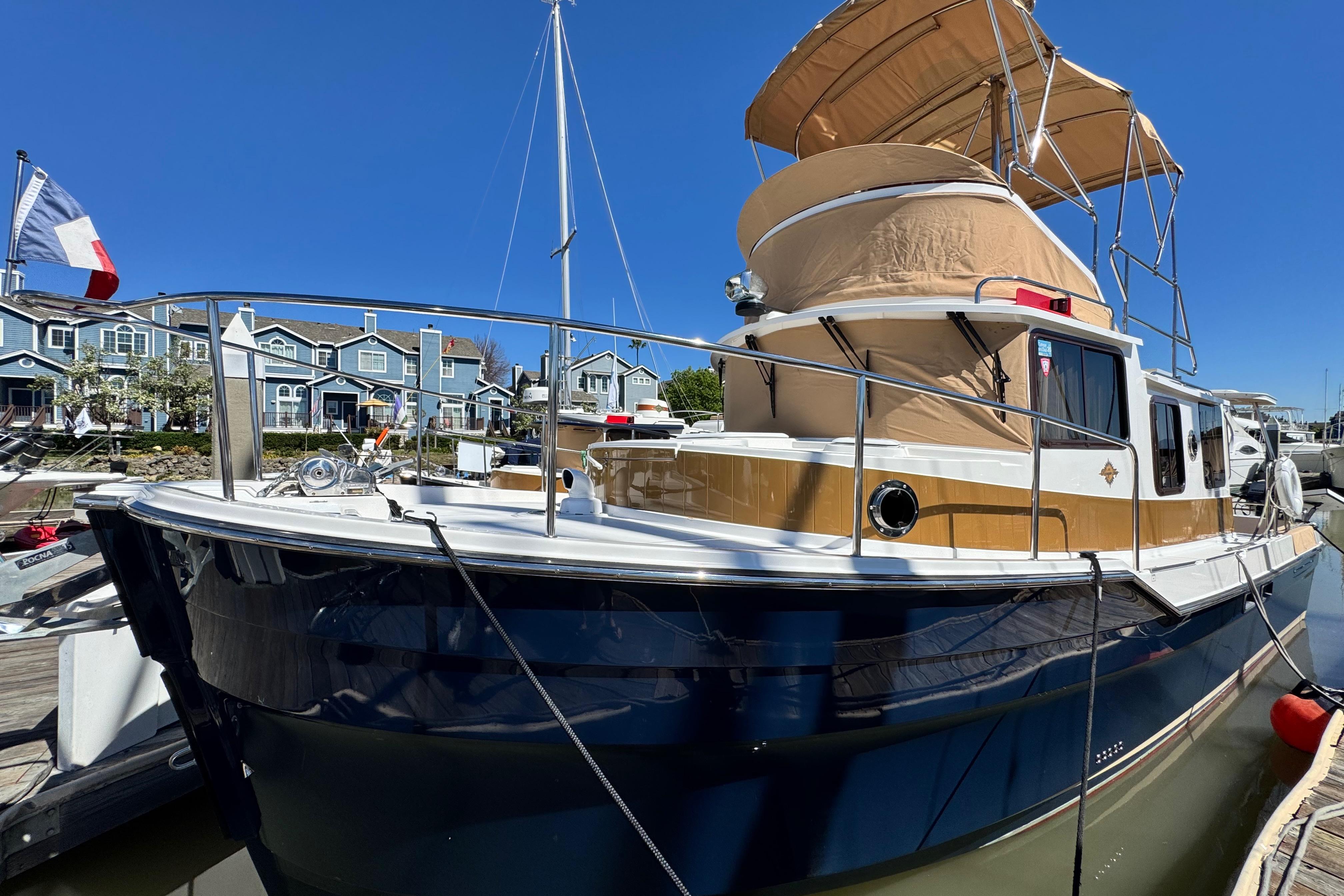 2019 Ranger Tugs R-31 CB boat docked, featuring a blue hull and tan canopy.
