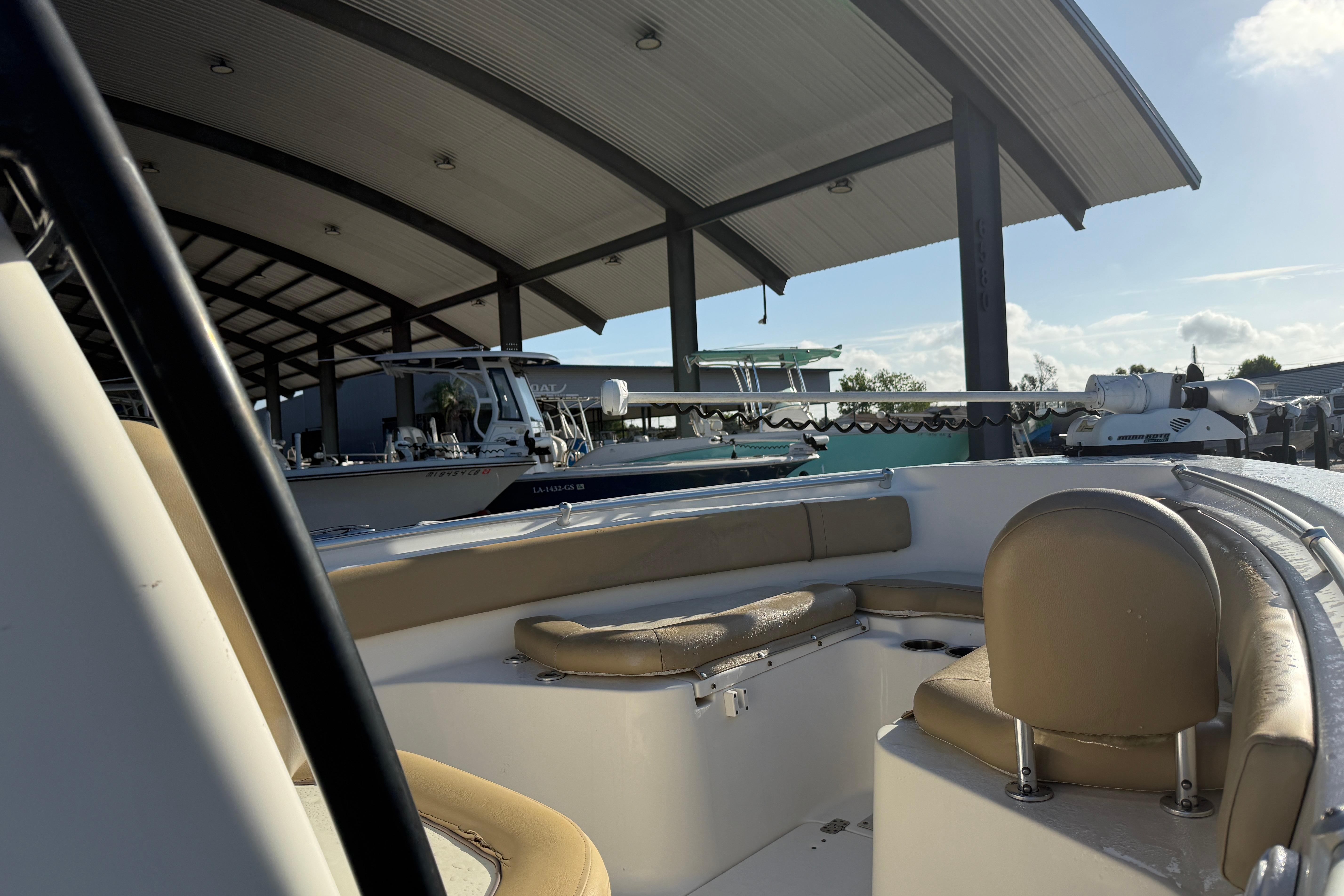 2016 Key West 239 FS boat under covered dock, featuring tan seating and modern design.