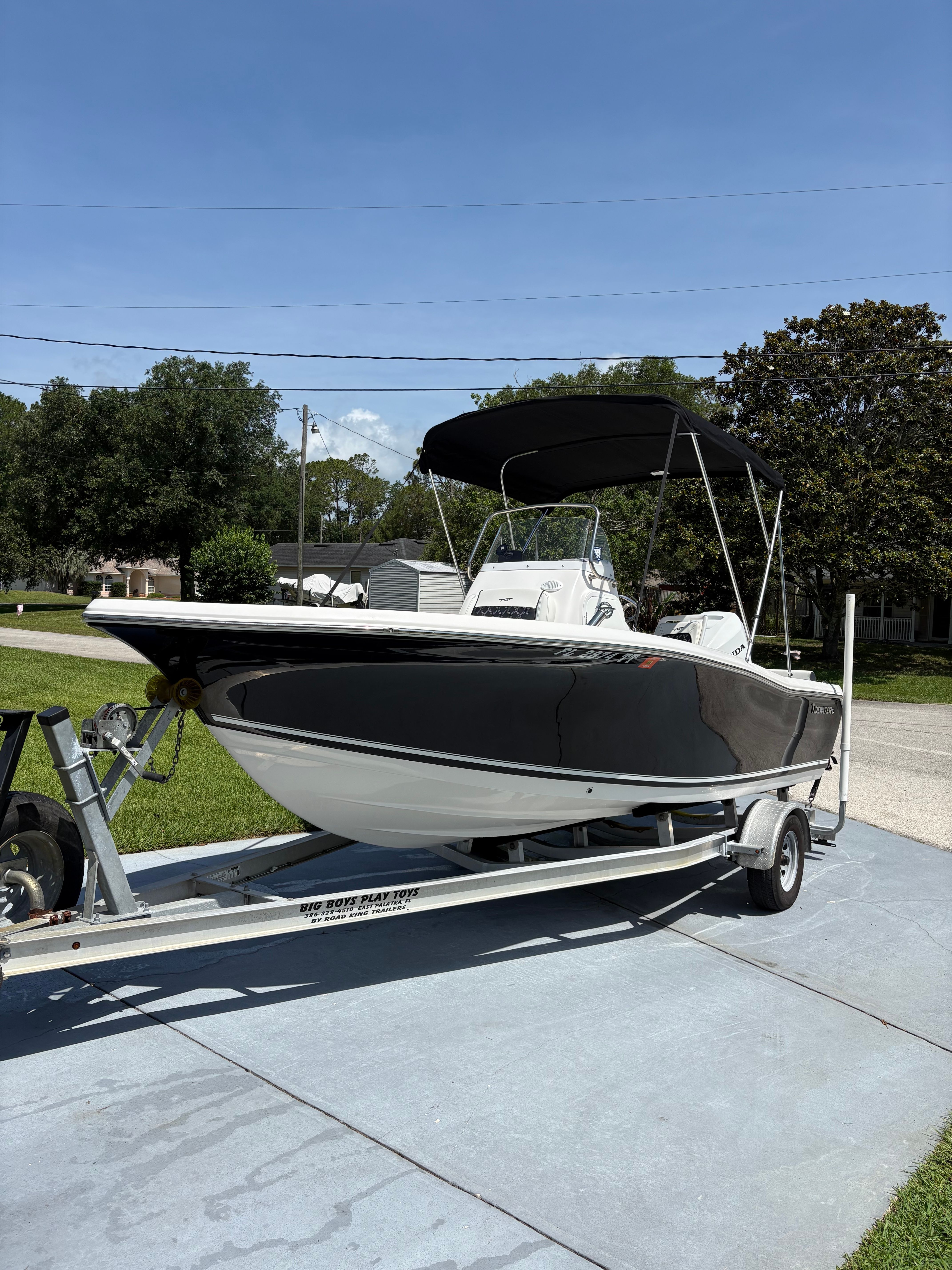 A 2024 Tidewater 198 CC Adventure boat on a trailer, featuring a black hull and sunshade.
