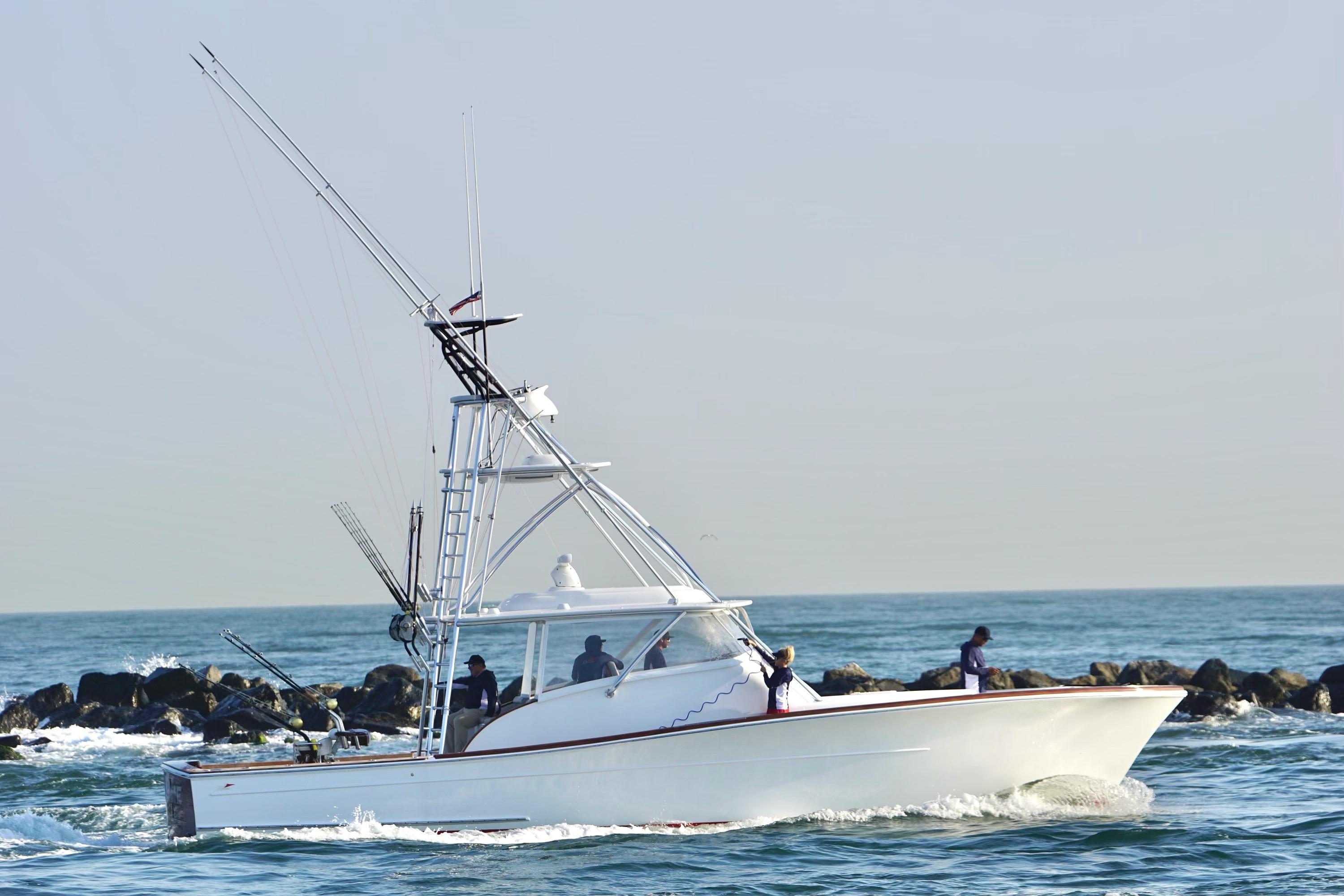 2026 Release Boatworks 46 Walkaround cruising on the ocean near rocky shoreline.