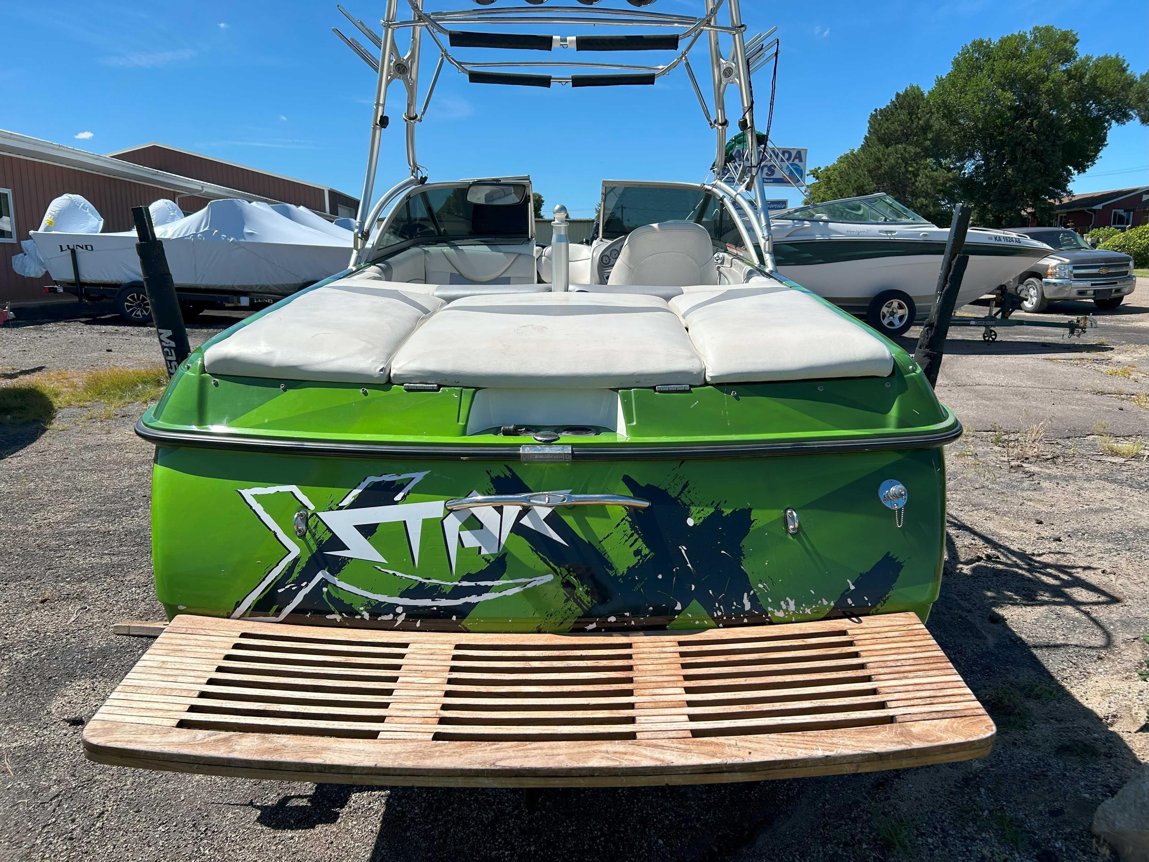 2002 MasterCraft XStar boat with green exterior and wooden swim platform.