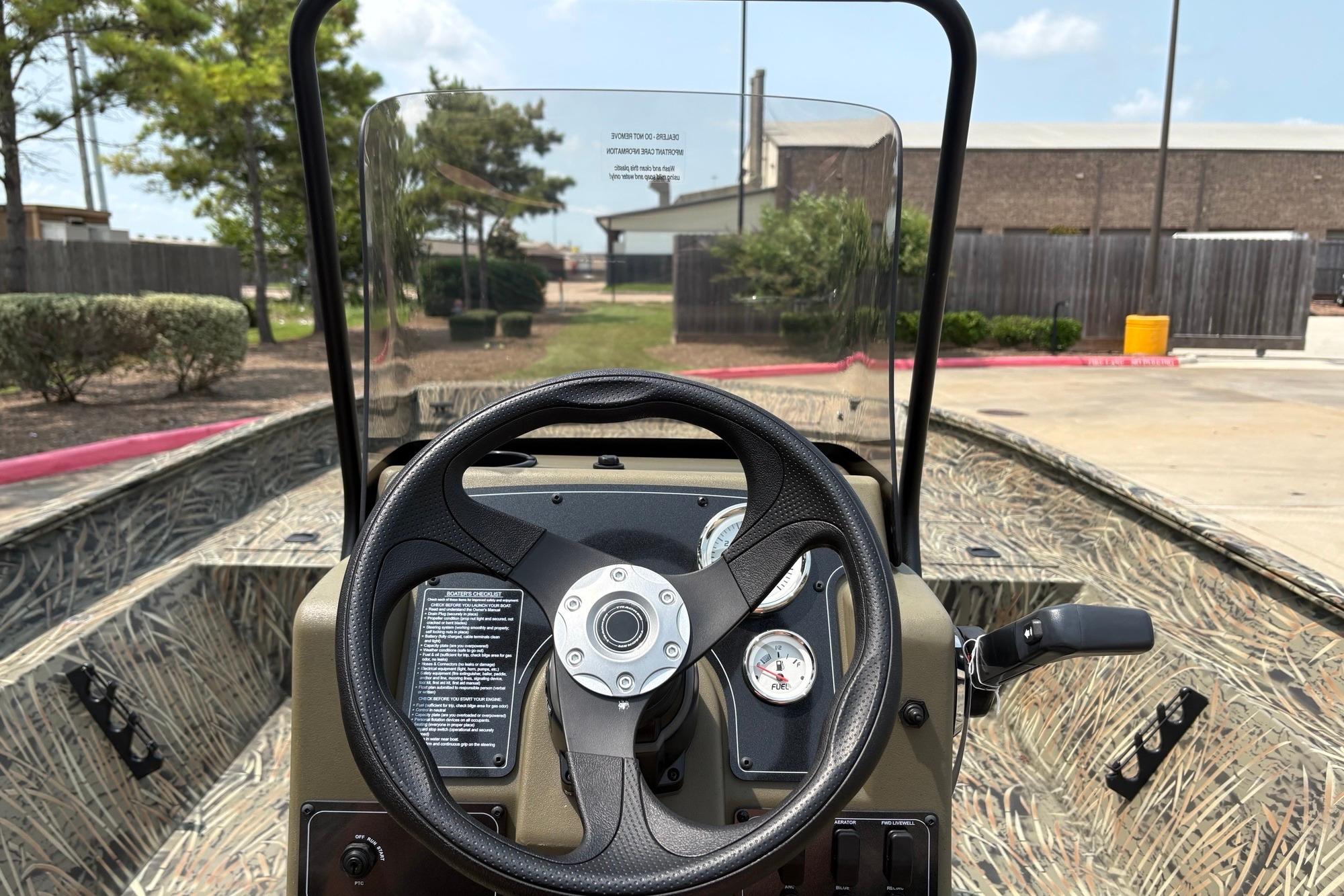 2026 Tracker Grizzly 2072 CC boat dashboard with steering wheel and gauges, outdoors.