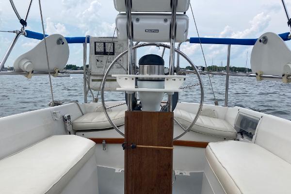 Cockpit of 1989 Catalina 30 sailboat with steering wheel and seating, on calm water.