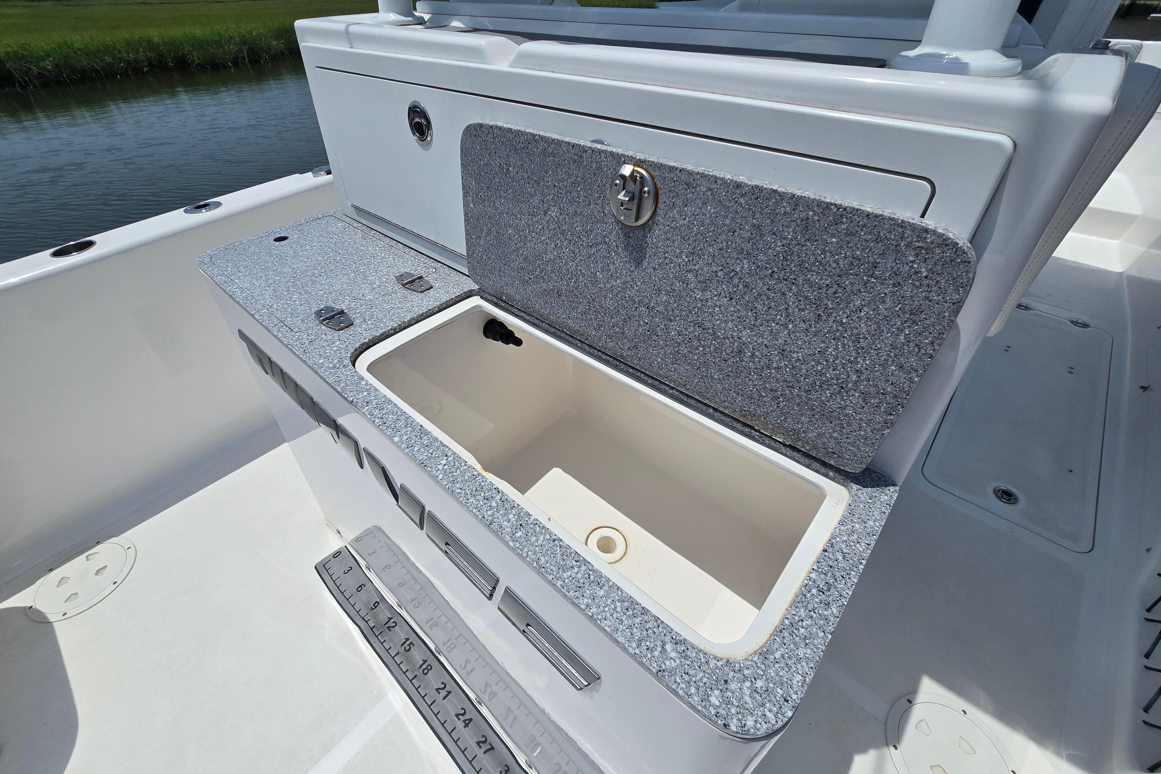 2021 Twin Vee 280 GFX CC boat with open storage compartment and ruler on deck.