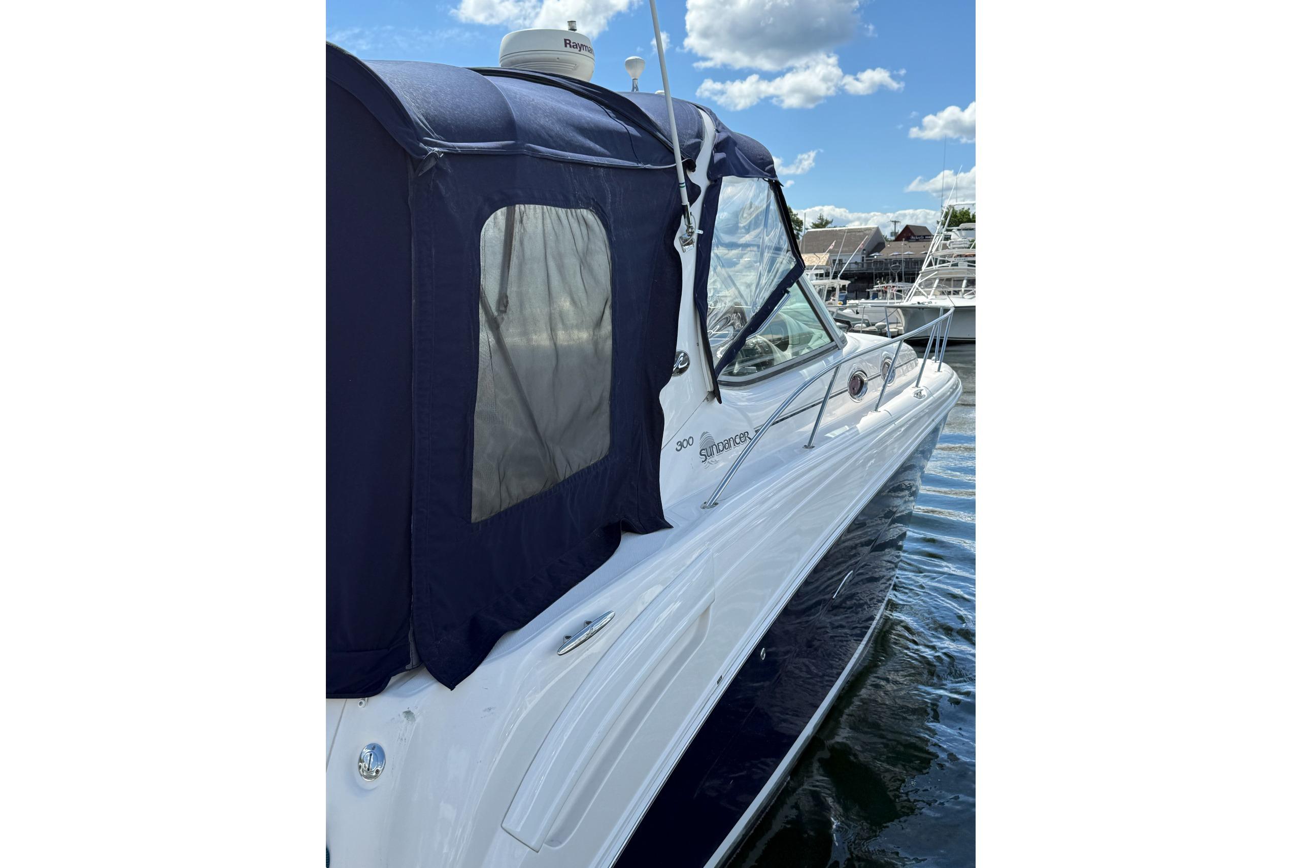 2006 Sea Ray 300 Sundancer boat with blue canopy on water.
