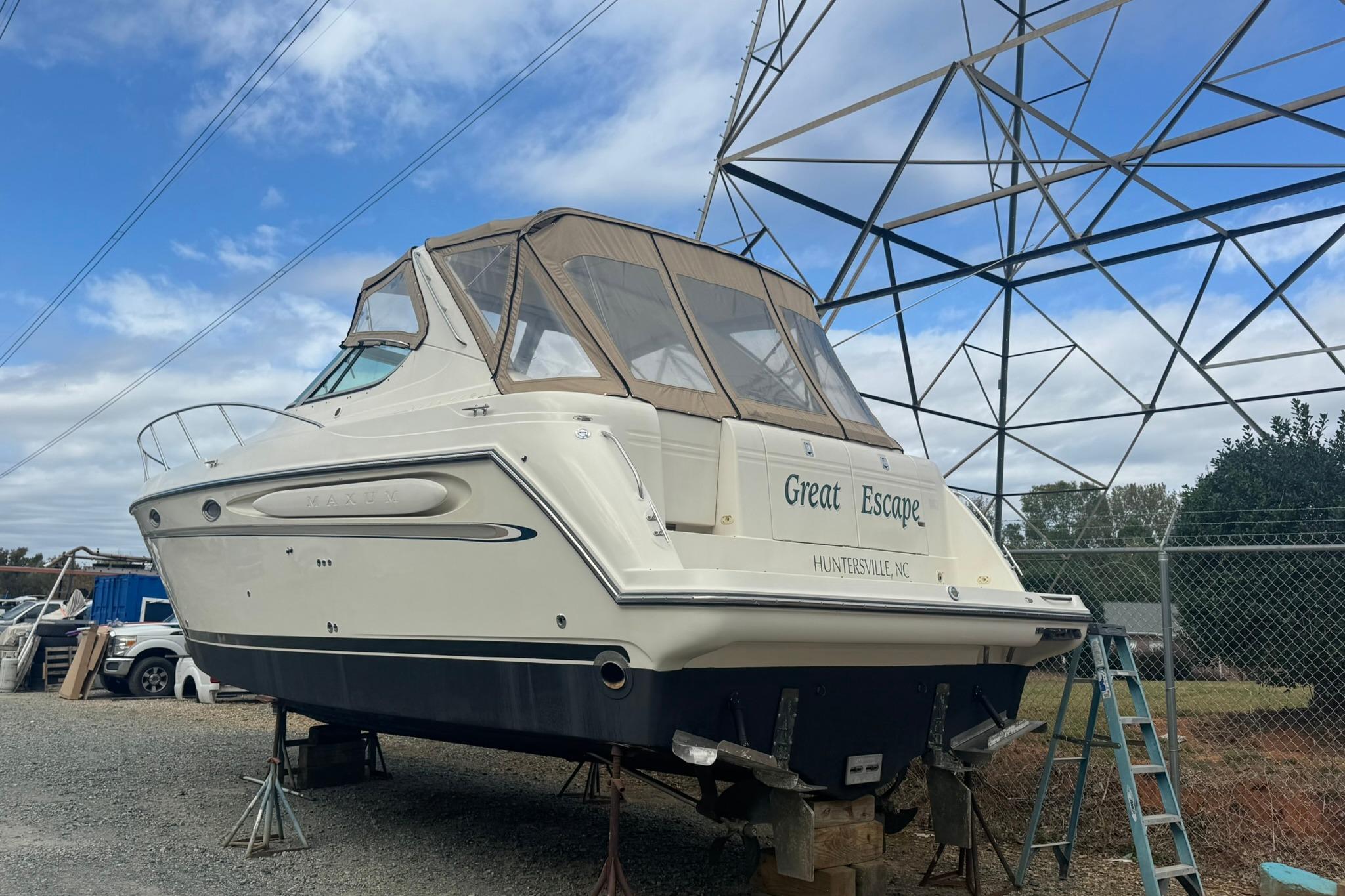 1998 Maxum 3700 SCR boat named "Great Escape" on dry dock under a clear sky.