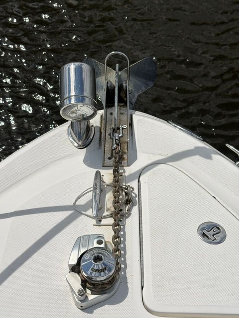 The bow of a boat with anchor and chain, resting on calm water.