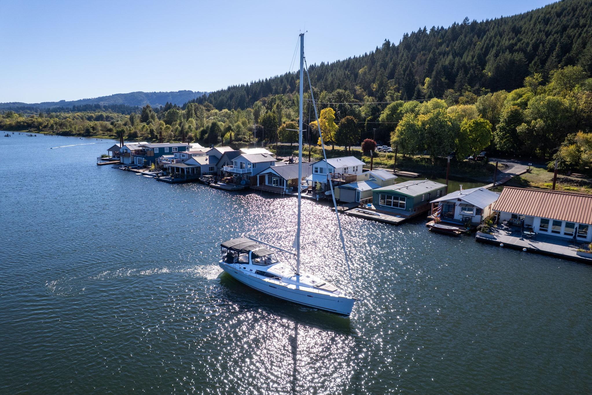 Sailboat Beneteau Oceanis 50 (2013) cruising near waterfront homes on a sunny day.