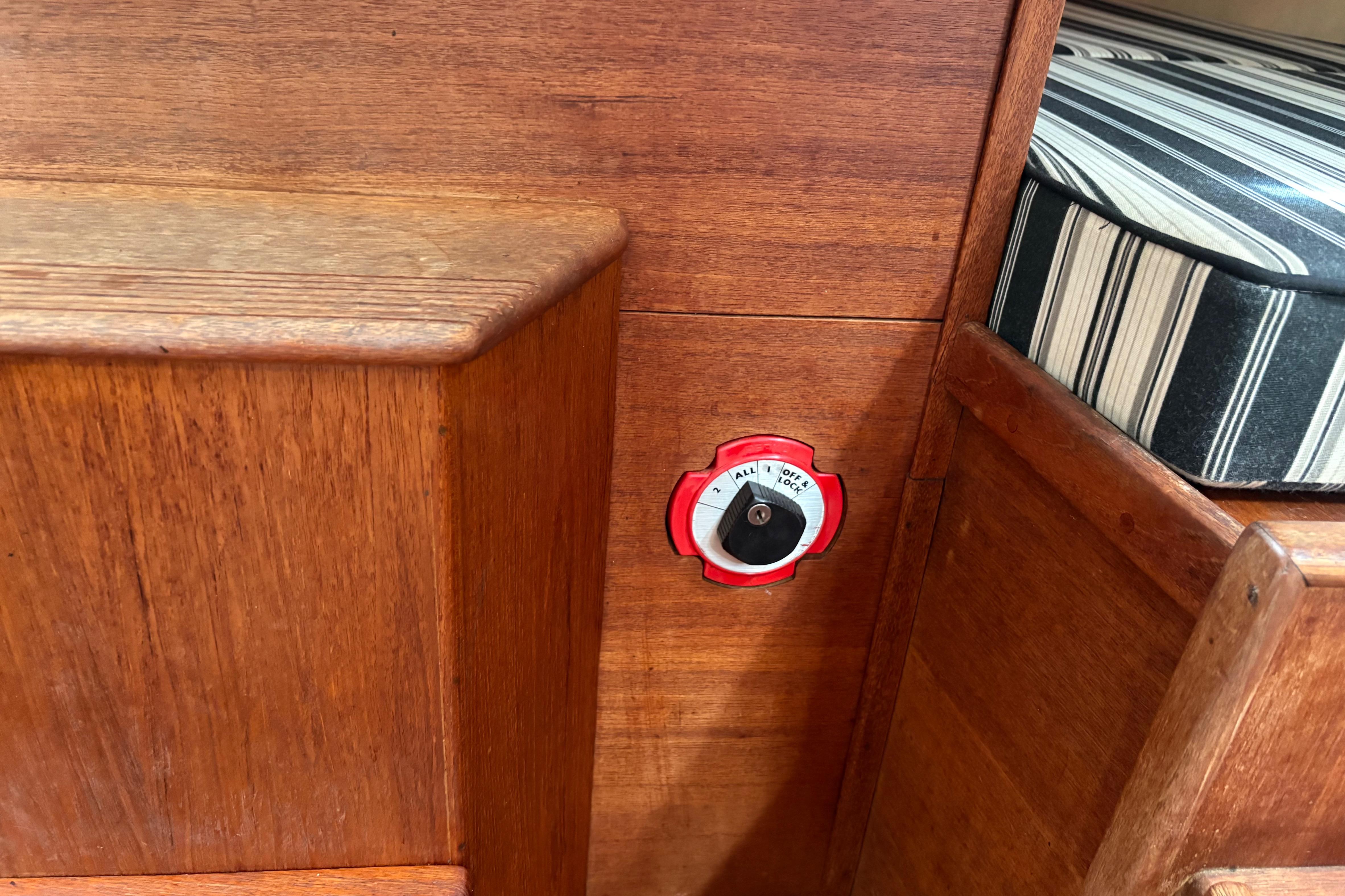 Wooden interior of 1981 Sabre 31 boat with a battery switch and striped cushion.
