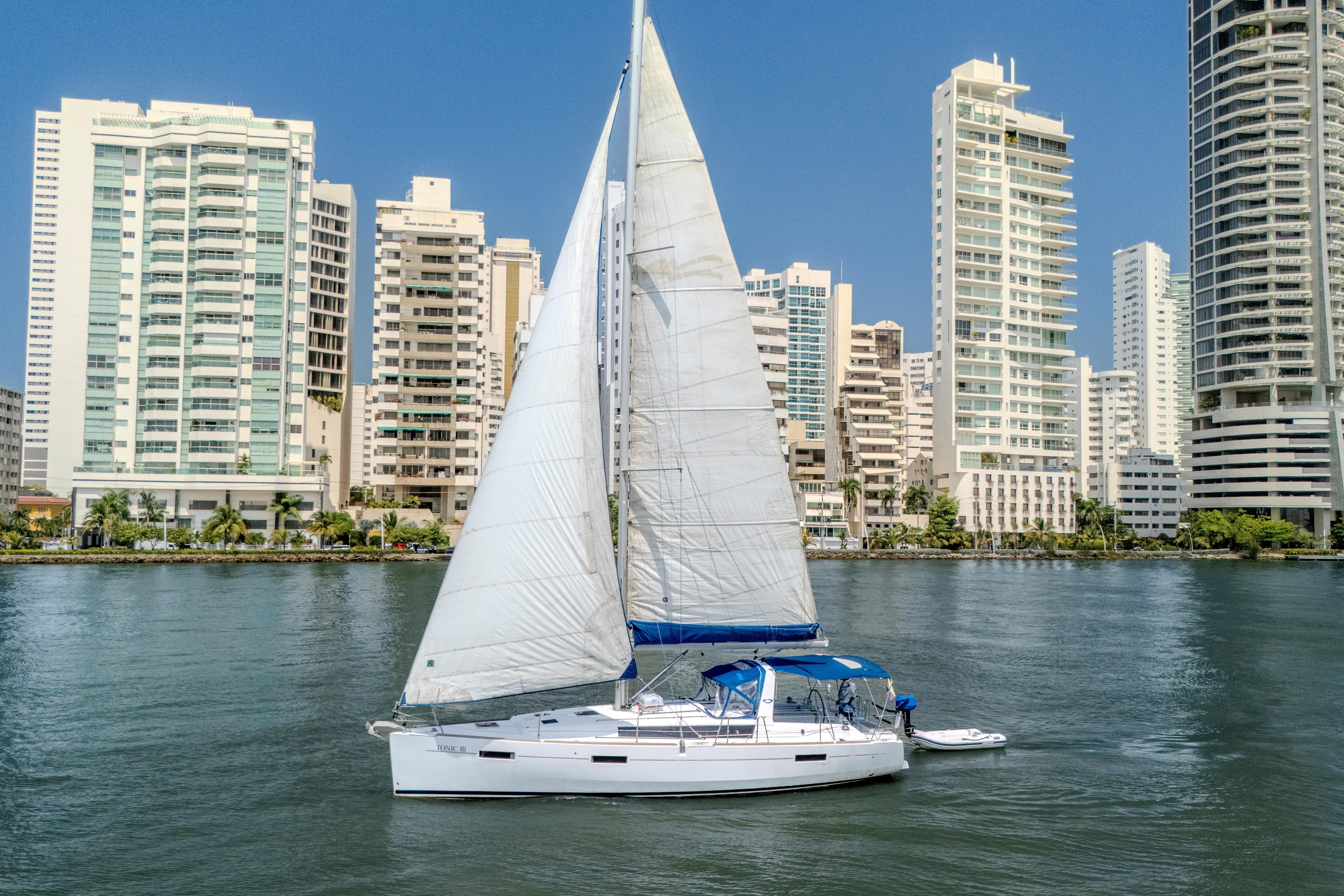 2013 Beneteau Oceanis 41 sailboat cruising near urban skyline on a sunny day.