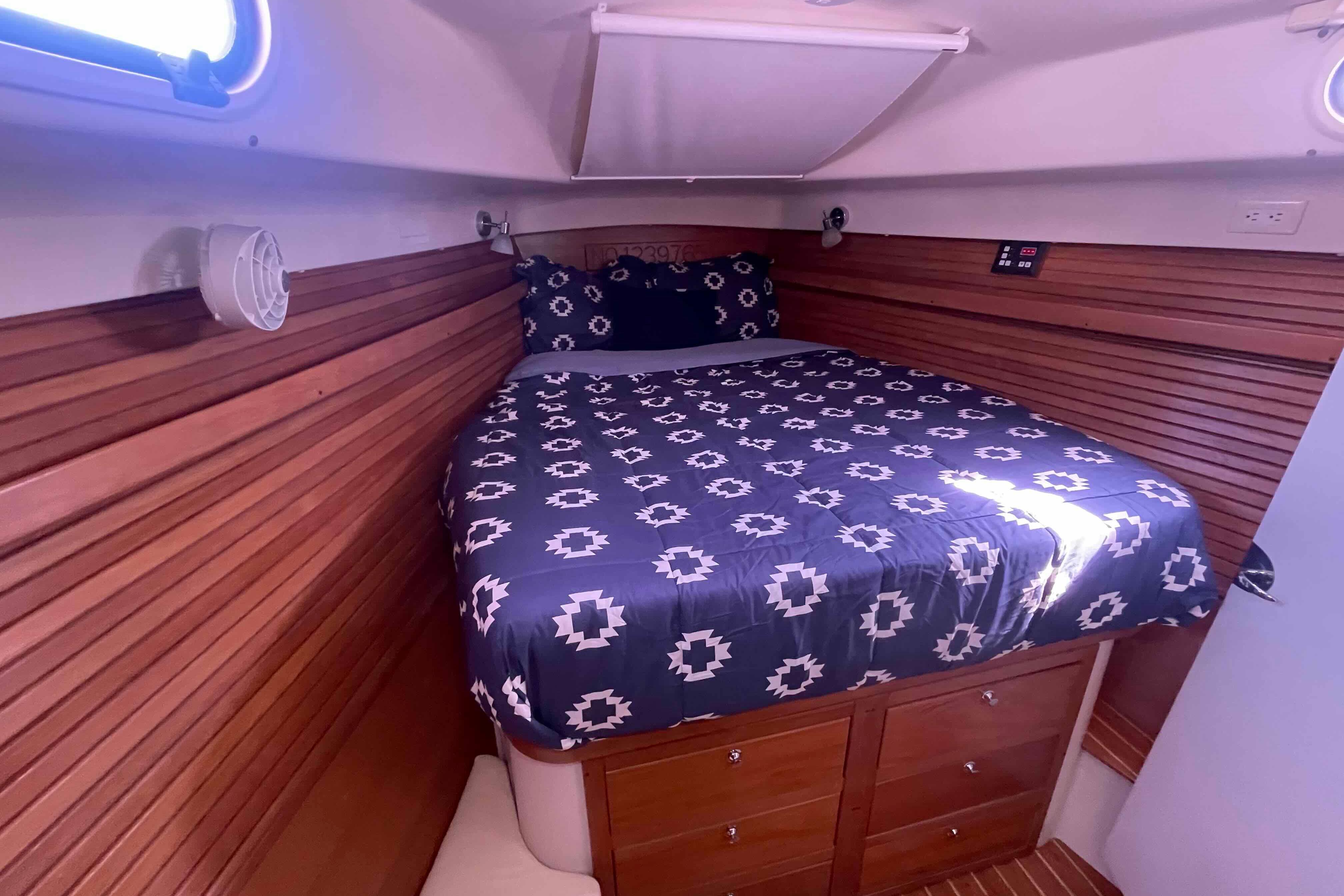 Cozy cabin interior of 2013 Catalina Morgan 440 with wooden paneling and patterned bedding.