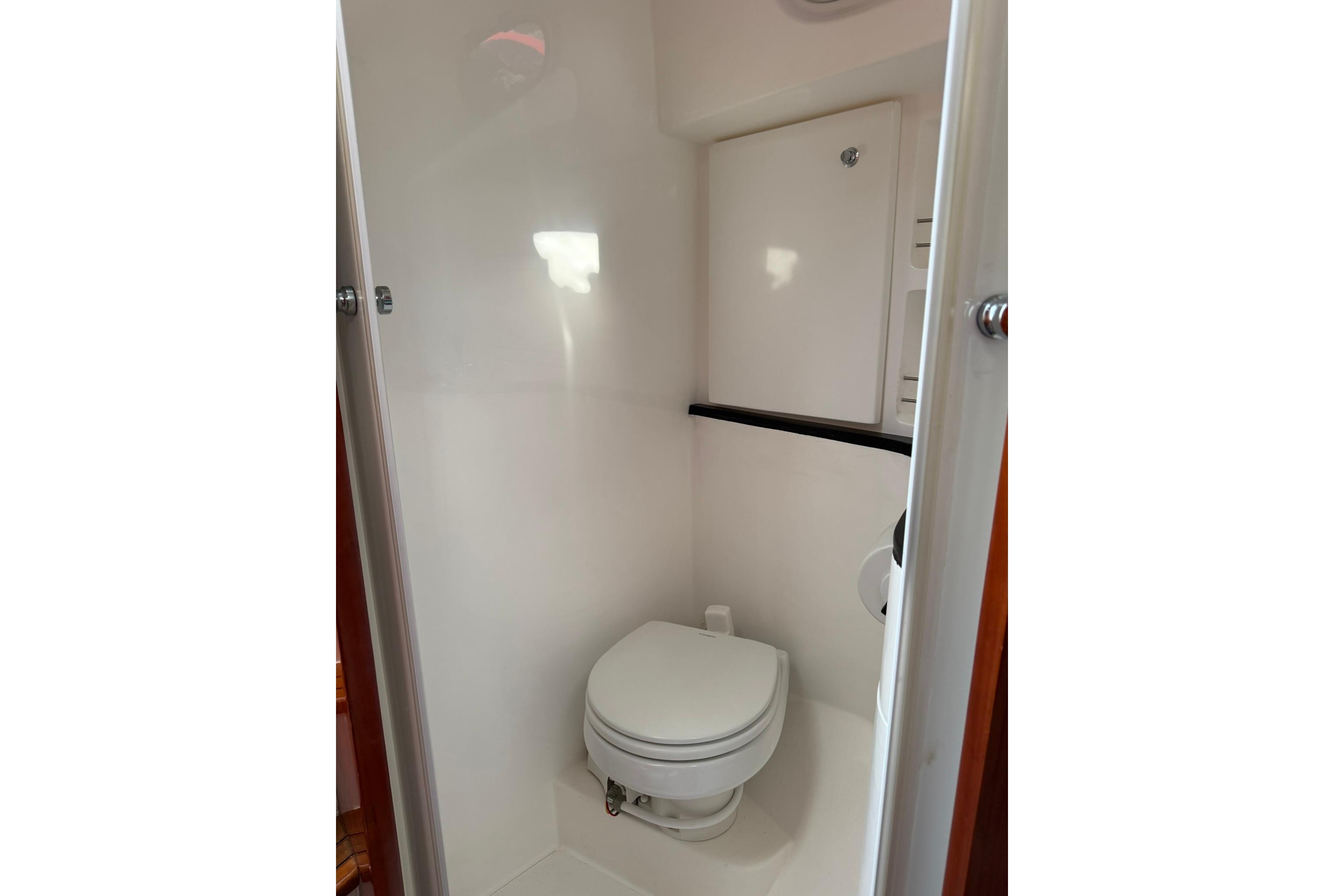 Compact marine bathroom in 2020 SeaPiper 35 boat, featuring a white toilet and storage cabinet.