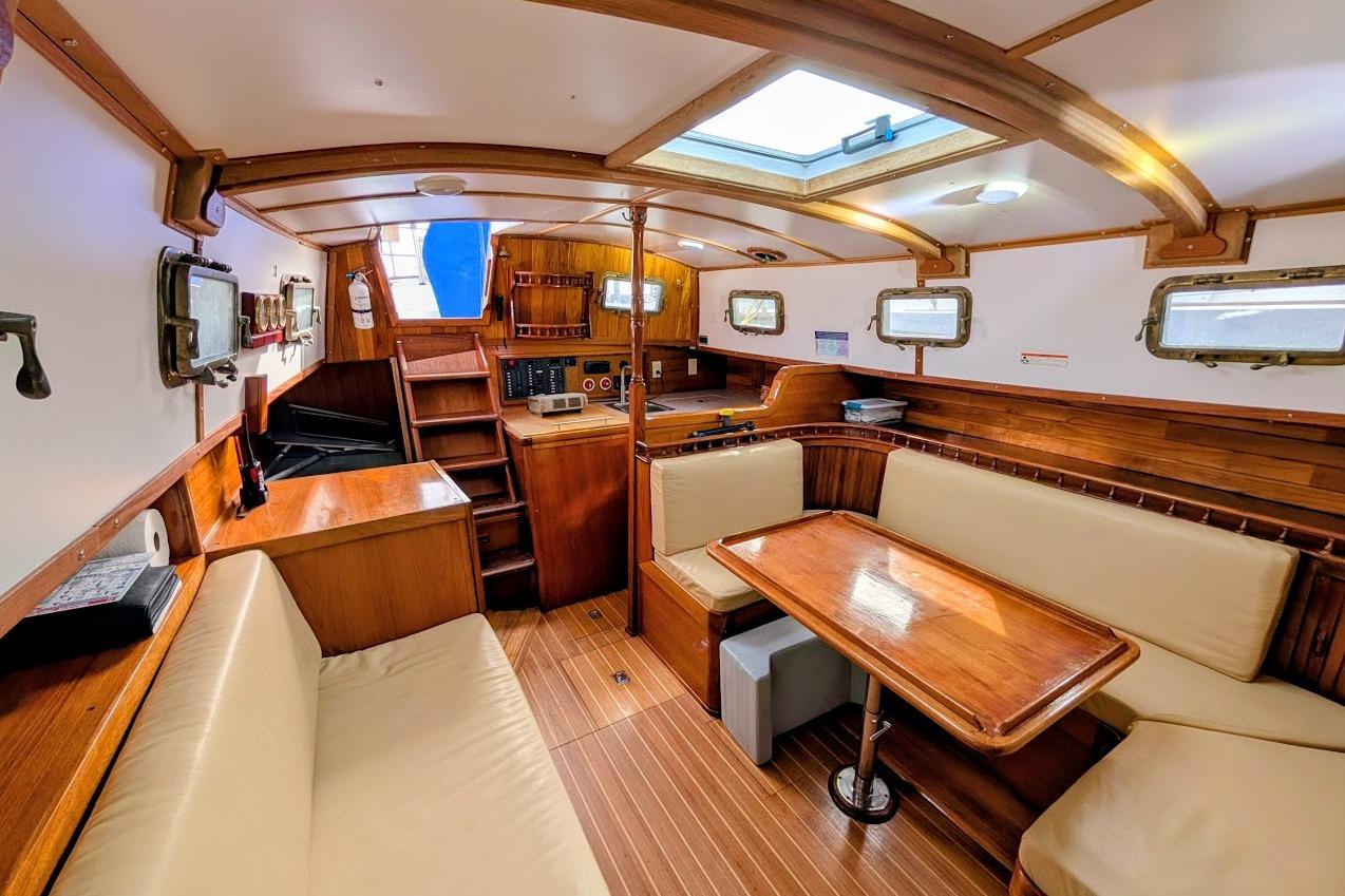 Interior of 1980 Island Trader 38 sailboat with wooden furnishings and cozy seating area.
