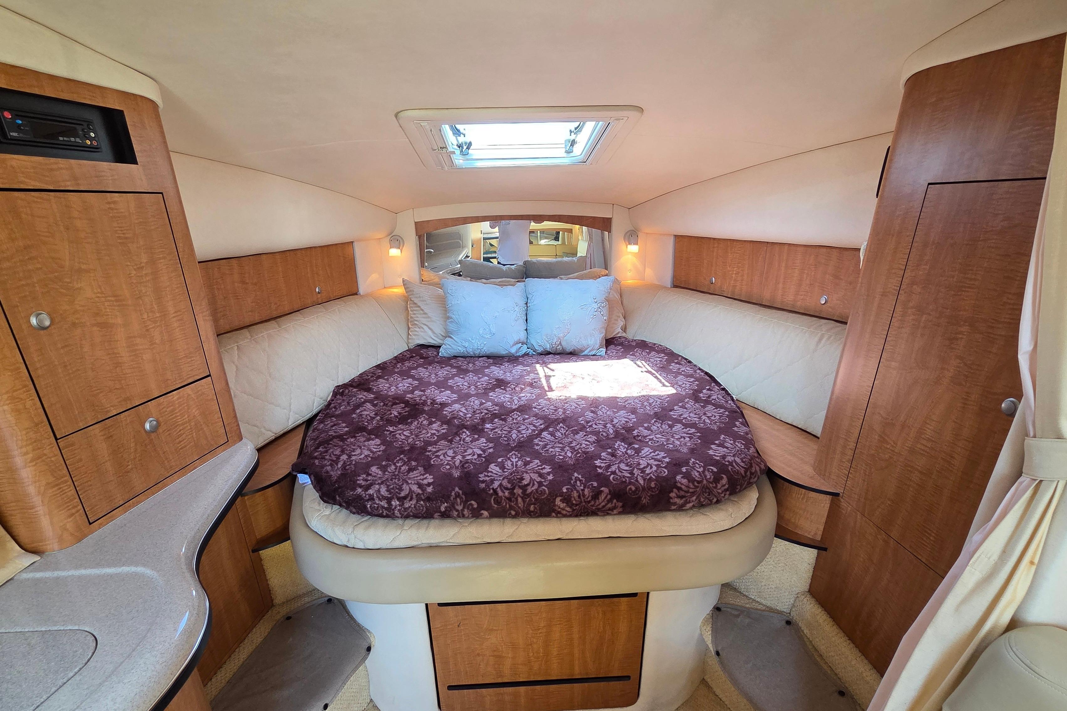 Luxurious cabin interior of 2006 Sea Ray Sundancer 320 with cozy bed and wooden cabinetry.