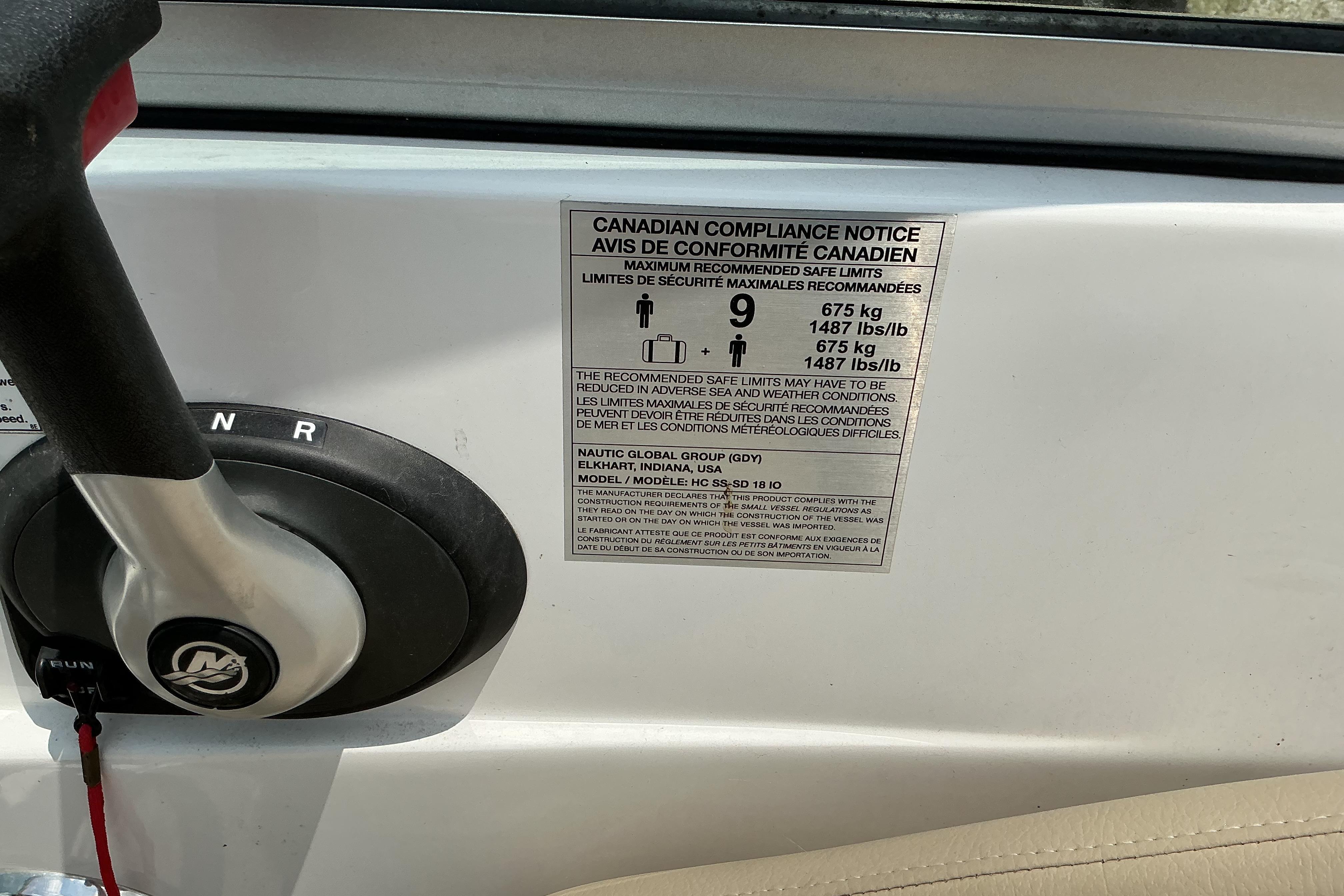 Close-up of a 2015 Hurricane SunDeck 187 IO boat compliance notice and control lever.