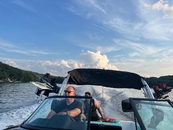 2022 MasterCraft NXT22 boat cruising on a lake under a blue sky.