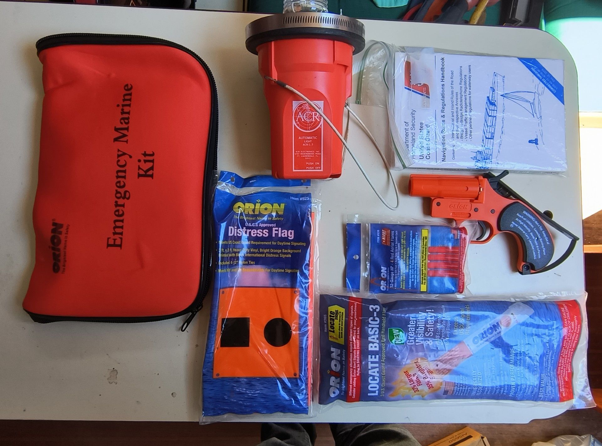 Emergency marine kit with flares and handbook on table.