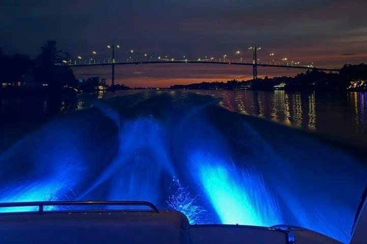 2008 Formula 400 Super Sport boat cruising under illuminated bridge at sunset with blue water lights.