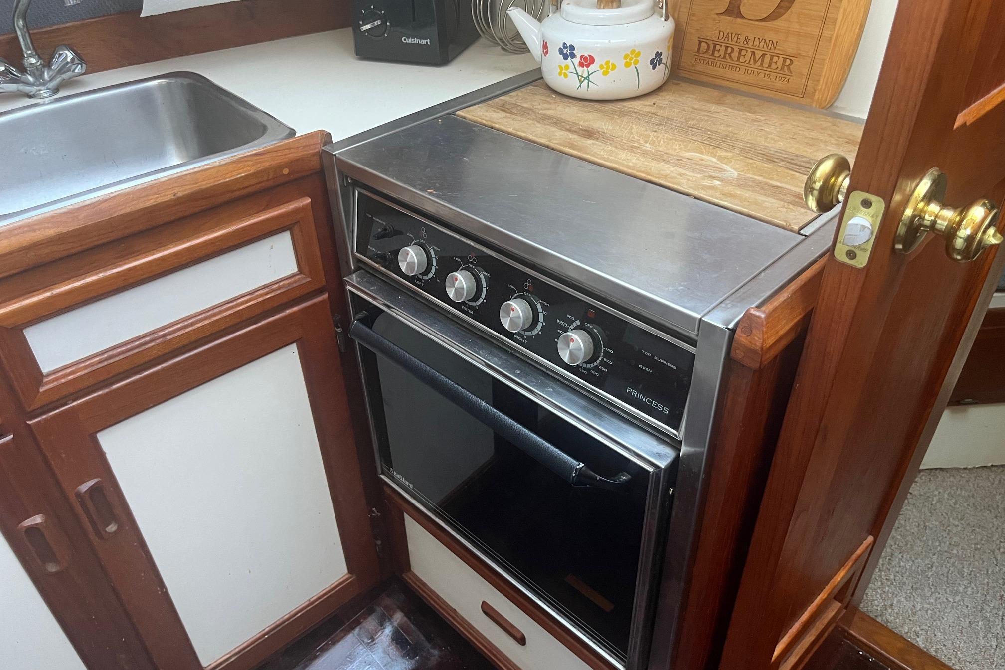 Compact kitchen area in a 1990 Cooper Prowler 35 boat with stove and sink.