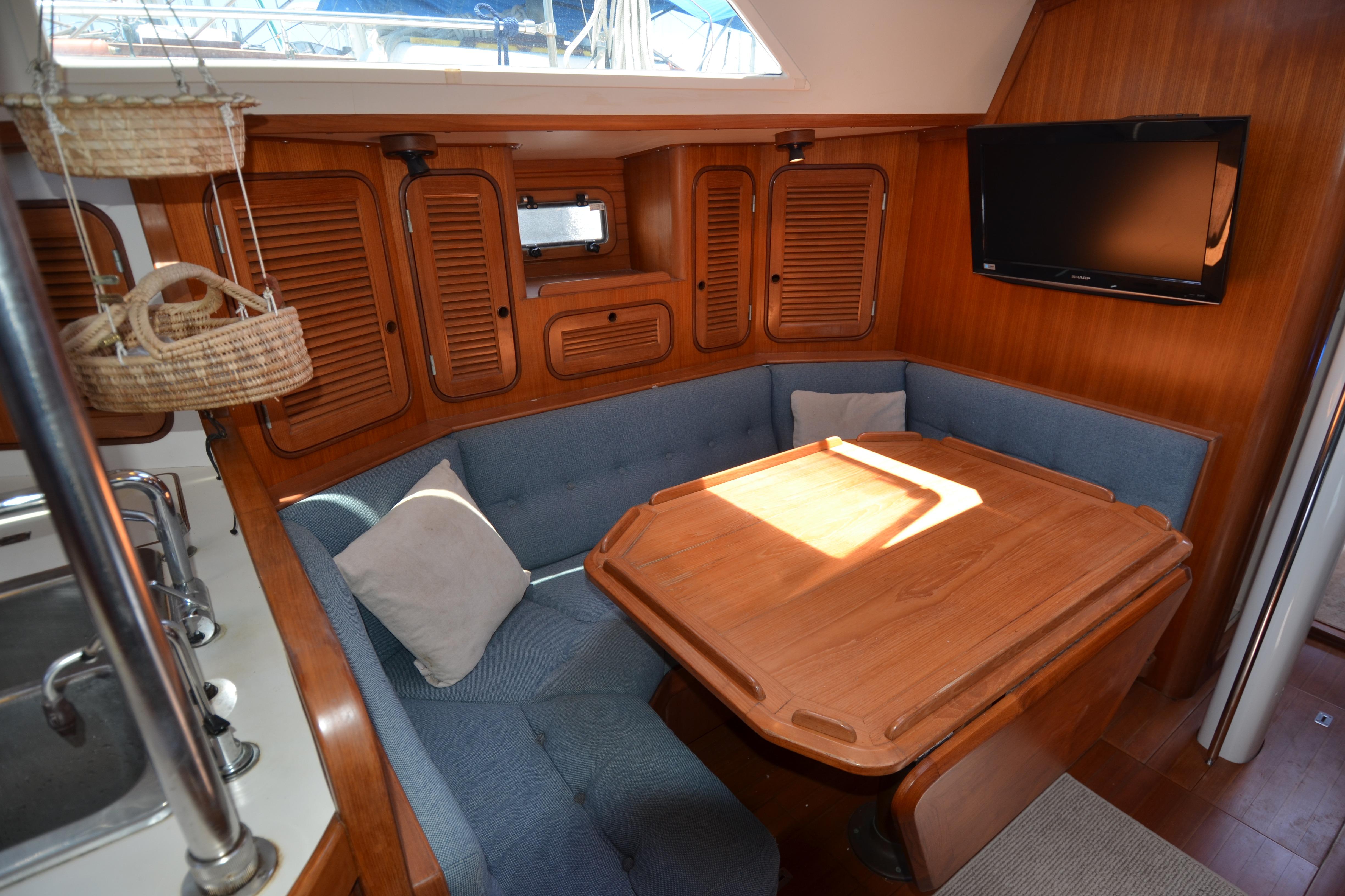 Cozy interior of 1987 Norseman 400 sailboat with wooden dining area and blue seating.