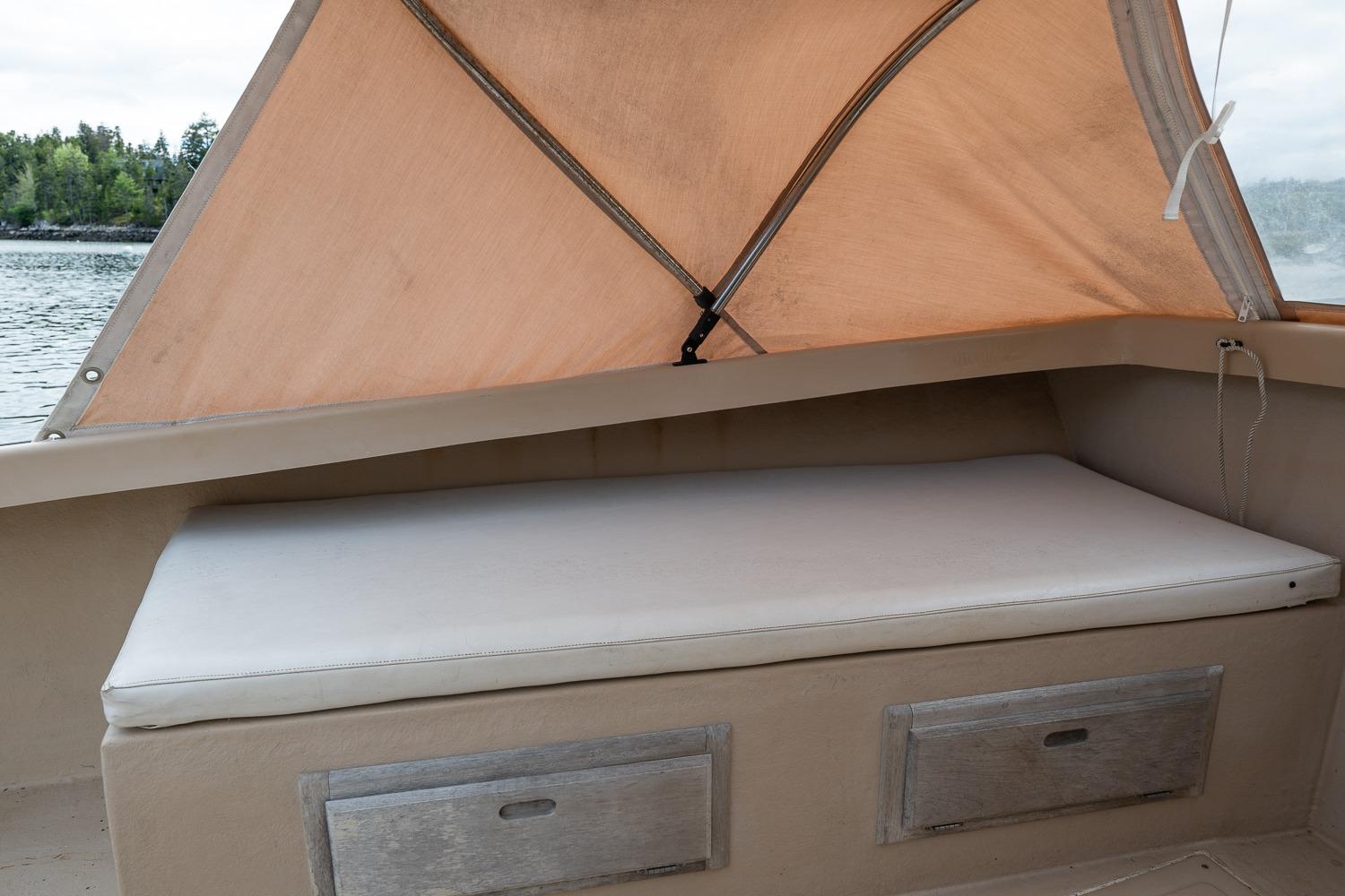 Cushioned seating area on 1989 Ellis 24 Open boat with canopy and storage drawers.