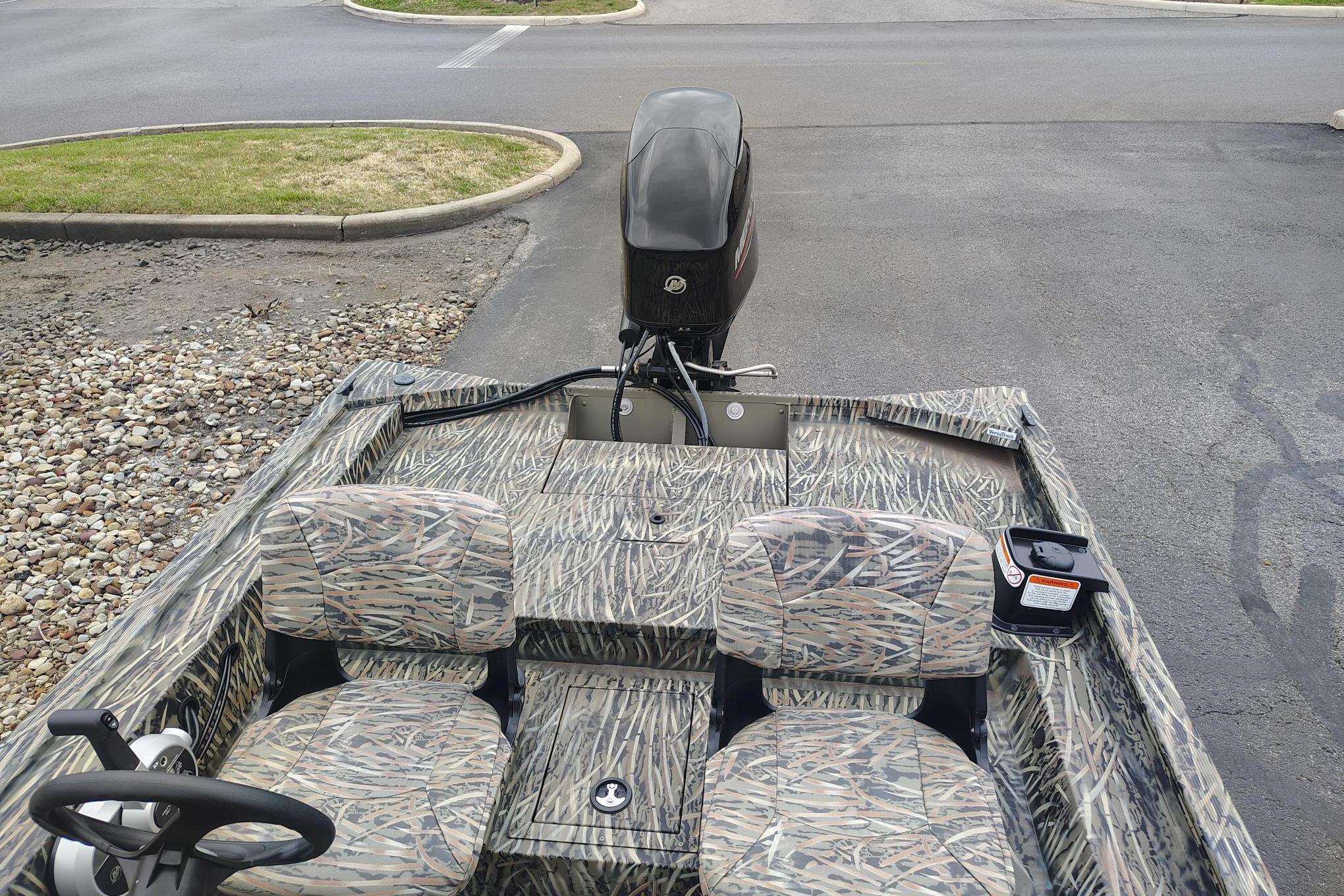 2026 Tracker Grizzly 1754 SC boat with camouflage seats and outboard motor in parking lot.