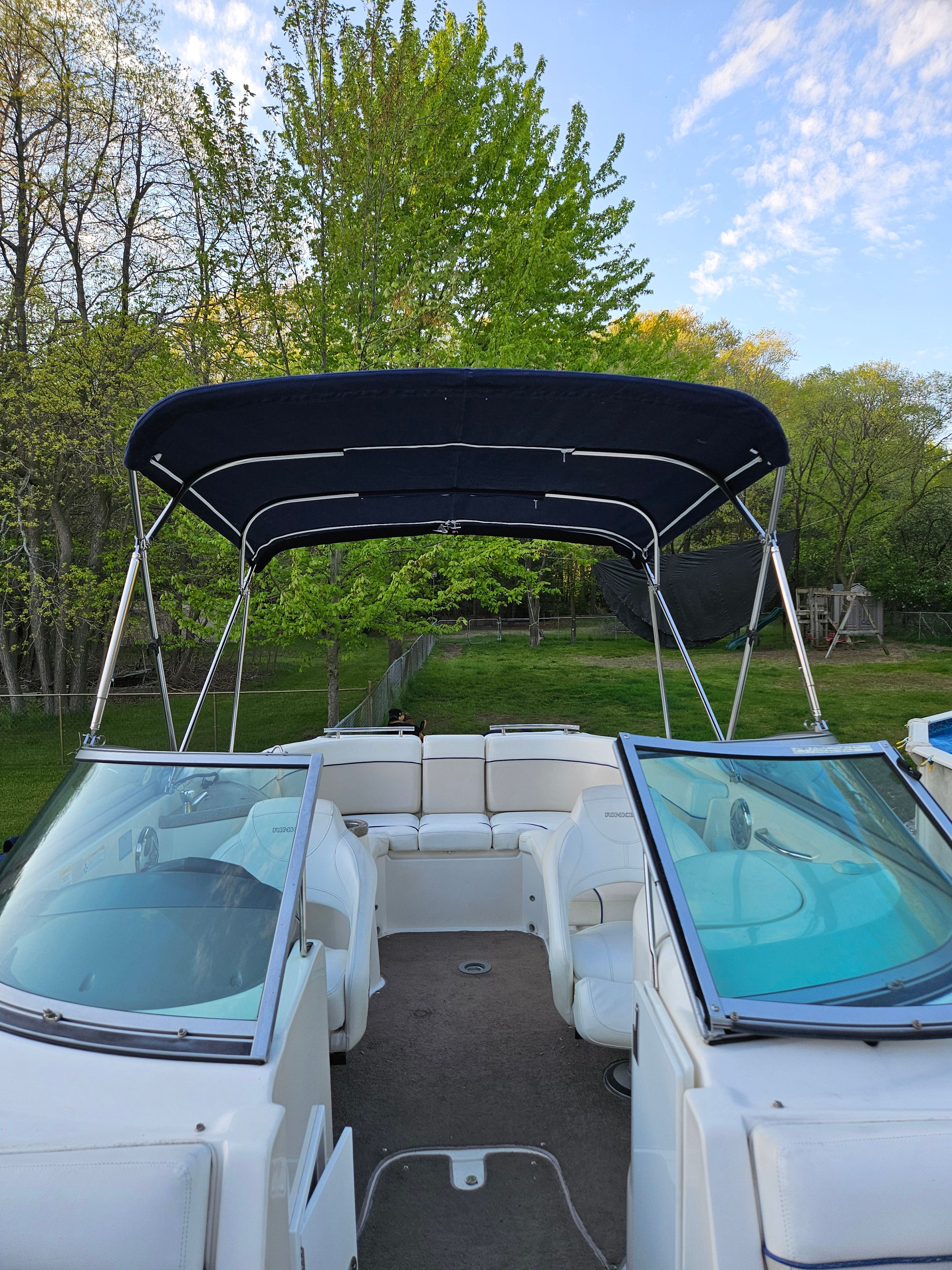 2009 Rinker Captiva DB boat with canopy, parked in greenery.